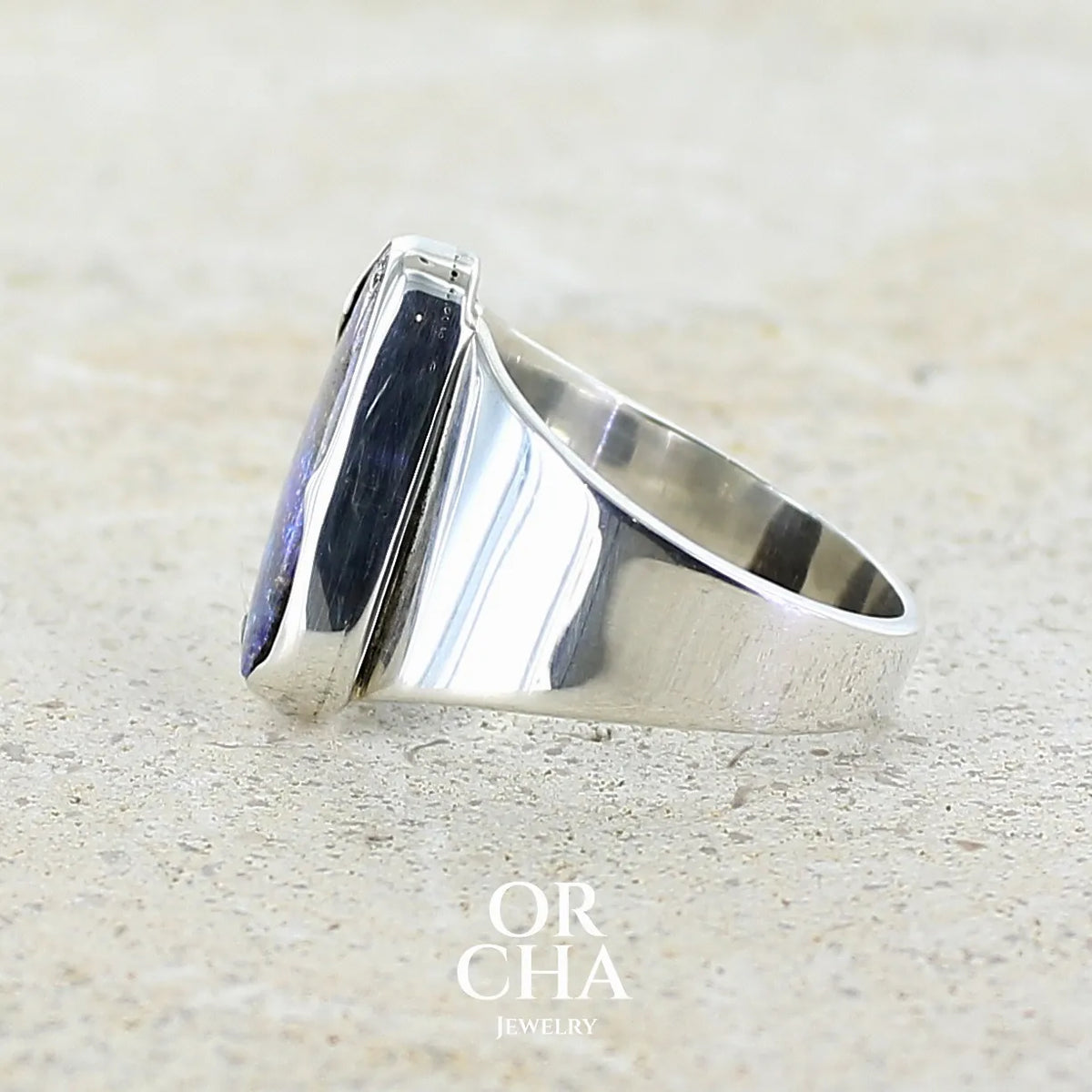Détail de l'anneau d'une bague pour femme en argent massif 925 sertie d'une opale boulder aux feux multicolores bleus violet et verts. Cabochon d'opale massive naturelle taillée en forme d'aile. Pierre de qualité opaque. Bijoux unique réalisé en taille 58 par Orcha Jewelry.