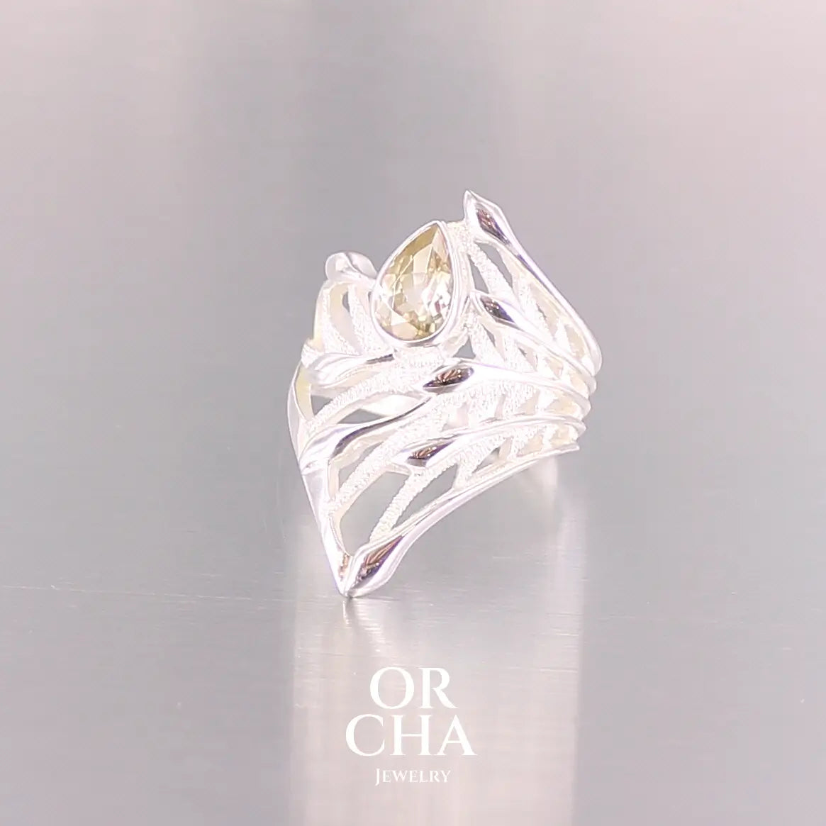 Pofil d'une grande Bague topaze impériale et argent massif illustrant un feuillage tropicale. Bijou pour femme sertie d'une Topaze impériale de couleur jaune pâle doré, pierre facettée en forme de poire. Pierre très lumineuse et propre à l'oeil. Bijoux unique, éthique et durable présenté dans un coffret de notre marque, prêt à offrir. Livraison offerte, certificat d'authenticité, service client.