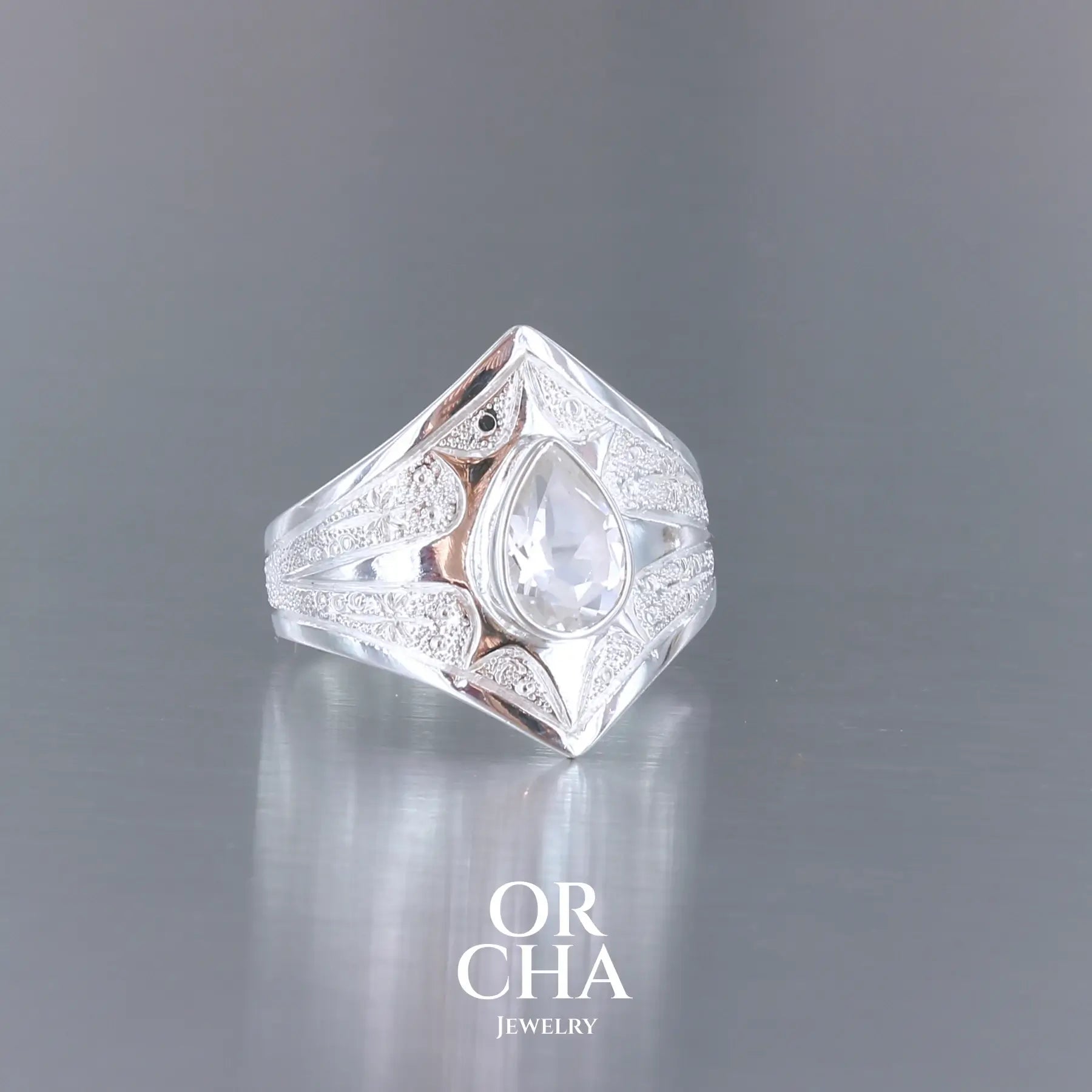 Bague pour femme en argent massif sculptées d'étoiles et autres corps célestes sertie d'une Topaze blanche.. Pierre facettée en forme de goutte, de couleur incolore, de qualité transparente ayant un très bel éclat. Disponible en plusieurs tailles. Bijoux unique, éthique et durable présenté dans un coffret de notre marque, prêt à offrir. Livraison offerte, certificat d'authenticité, service client.