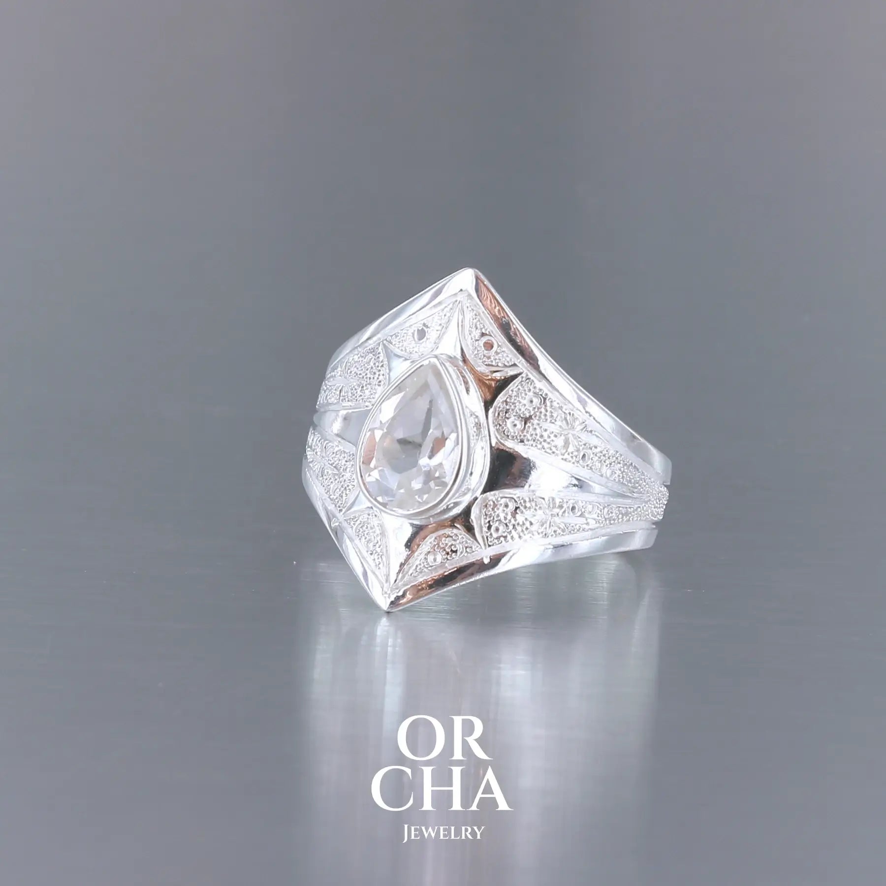 Bague pour femme en argent massif sculptées d'étoiles et autres corps célestes sertie d'une Topaze blanche.. Pierre facettée en forme de goutte, de couleur incolore, de qualité transparente ayant un très bel éclat. Disponible en plusieurs tailles. Bijoux unique, éthique et durable présenté dans un coffret de notre marque, prêt à offrir. Livraison offerte, certificat d'authenticité, service client.