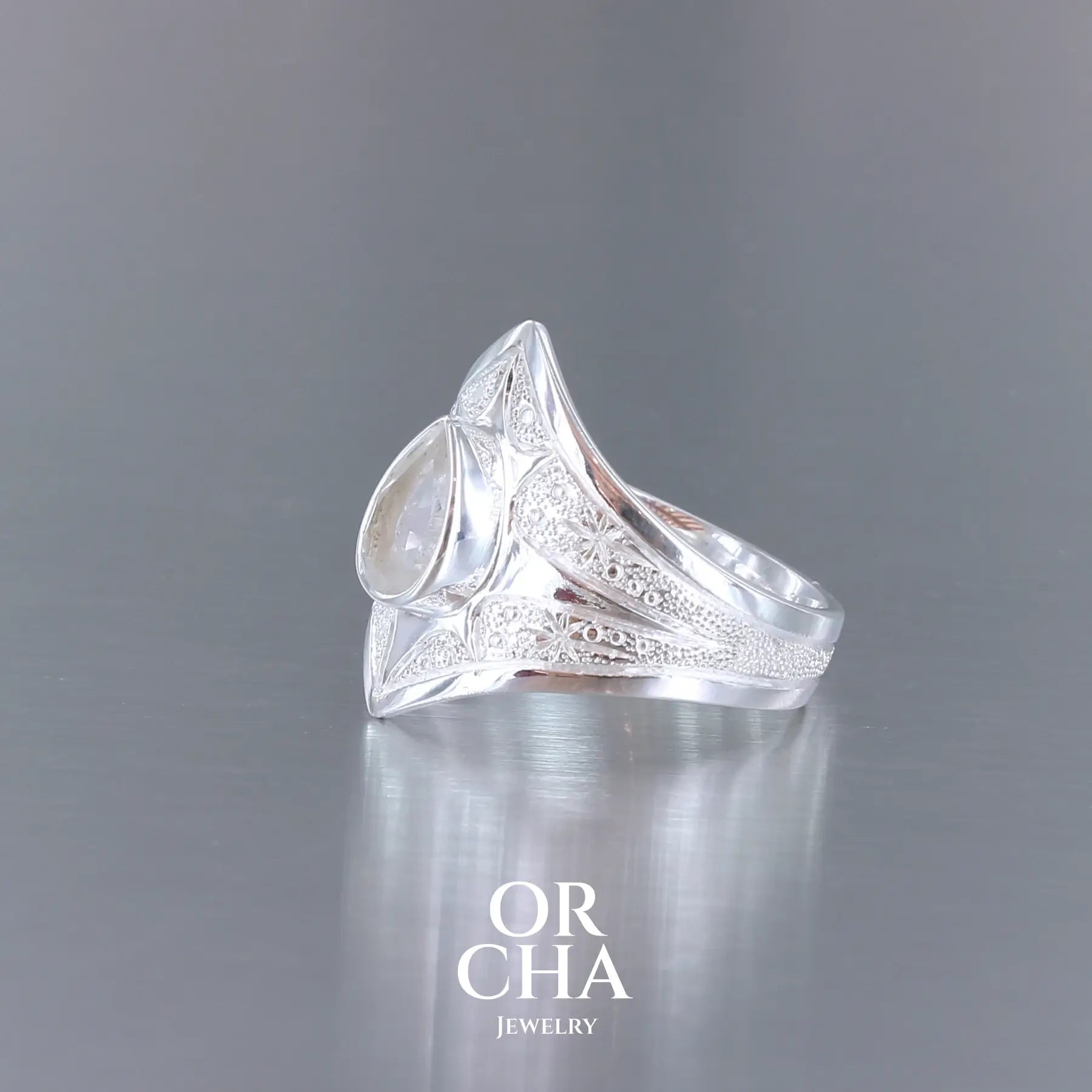 Bague pour femme en argent massif sculptées d'étoiles et autres corps célestes sertie d'une Topaze blanche.. Pierre facettée en forme de goutte, de couleur incolore, de qualité transparente ayant un très bel éclat. Disponible en plusieurs tailles. Bijoux unique, éthique et durable présenté dans un coffret de notre marque, prêt à offrir. Livraison offerte, certificat d'authenticité, service client.