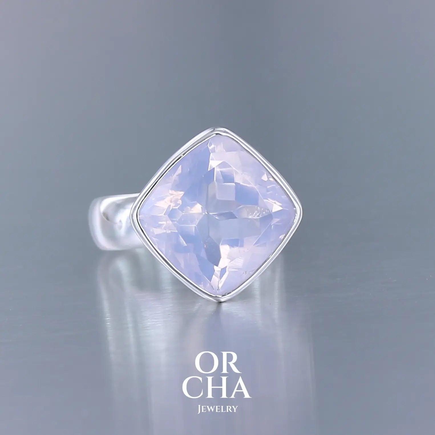 Bague cocktail pour femme en argent massif sertie d'un Quartz lavande. Pierre facettée de forme carrée de qualité transparente, propre à l'oeil. Pierre naturelle de couleur violette pastel teintée de rose avec de légers reflets opalescents. Plusieurs tailles disponibles. Bijoux unique, éthique et durable présenté dans un coffret de notre marque, prêt à offrir. Livraison offerte, certificat d'authenticité, service client.