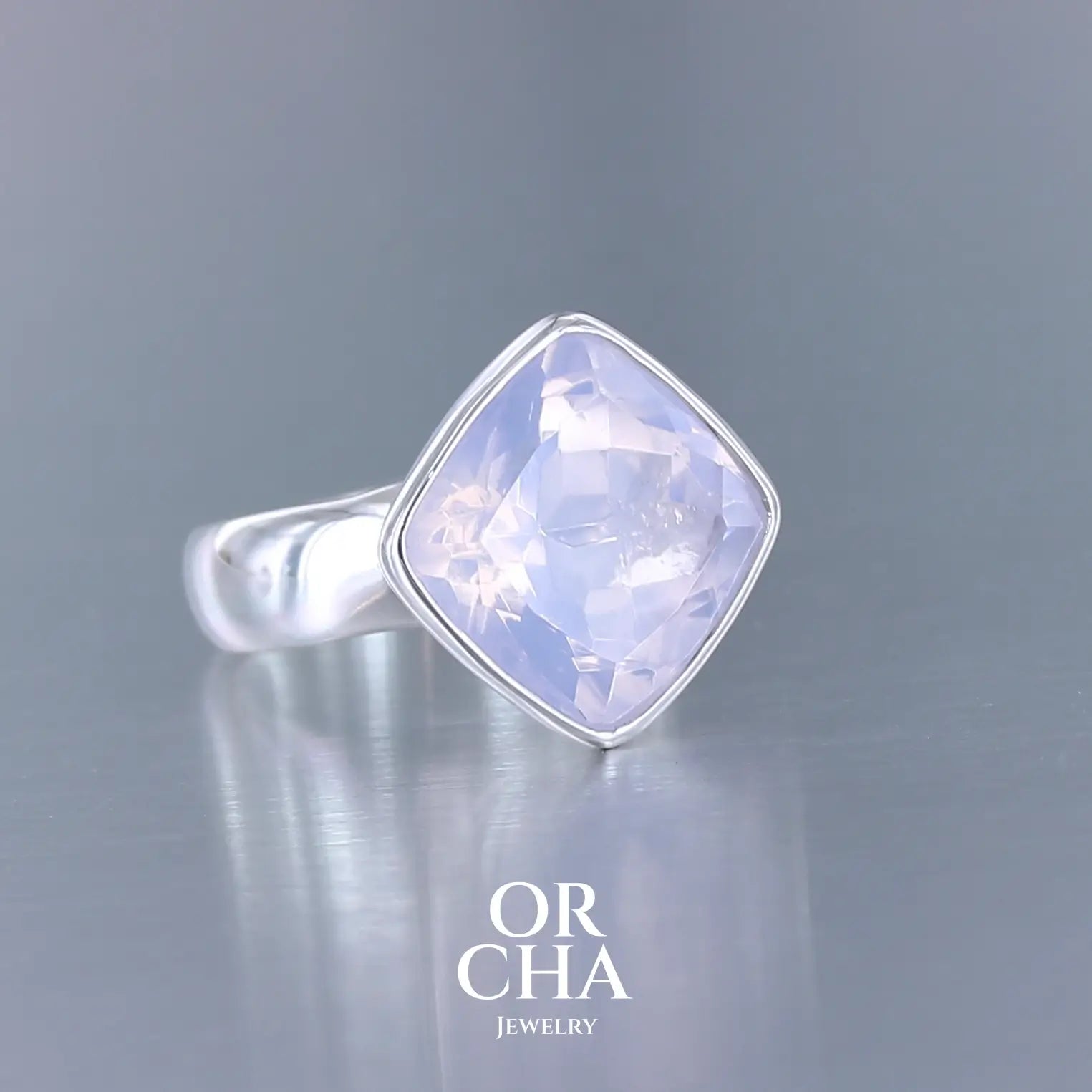 Bague cocktail pour femme en argent massif sertie d'un Quartz lavande. Pierre facettée de forme carrée de qualité transparente, propre à l'oeil. Pierre naturelle de couleur violette pastel teintée de rose avec de légers reflets opalescents. Plusieurs tailles disponibles. Bijoux unique, éthique et durable présenté dans un coffret de notre marque, prêt à offrir. Livraison offerte, certificat d'authenticité, service client.