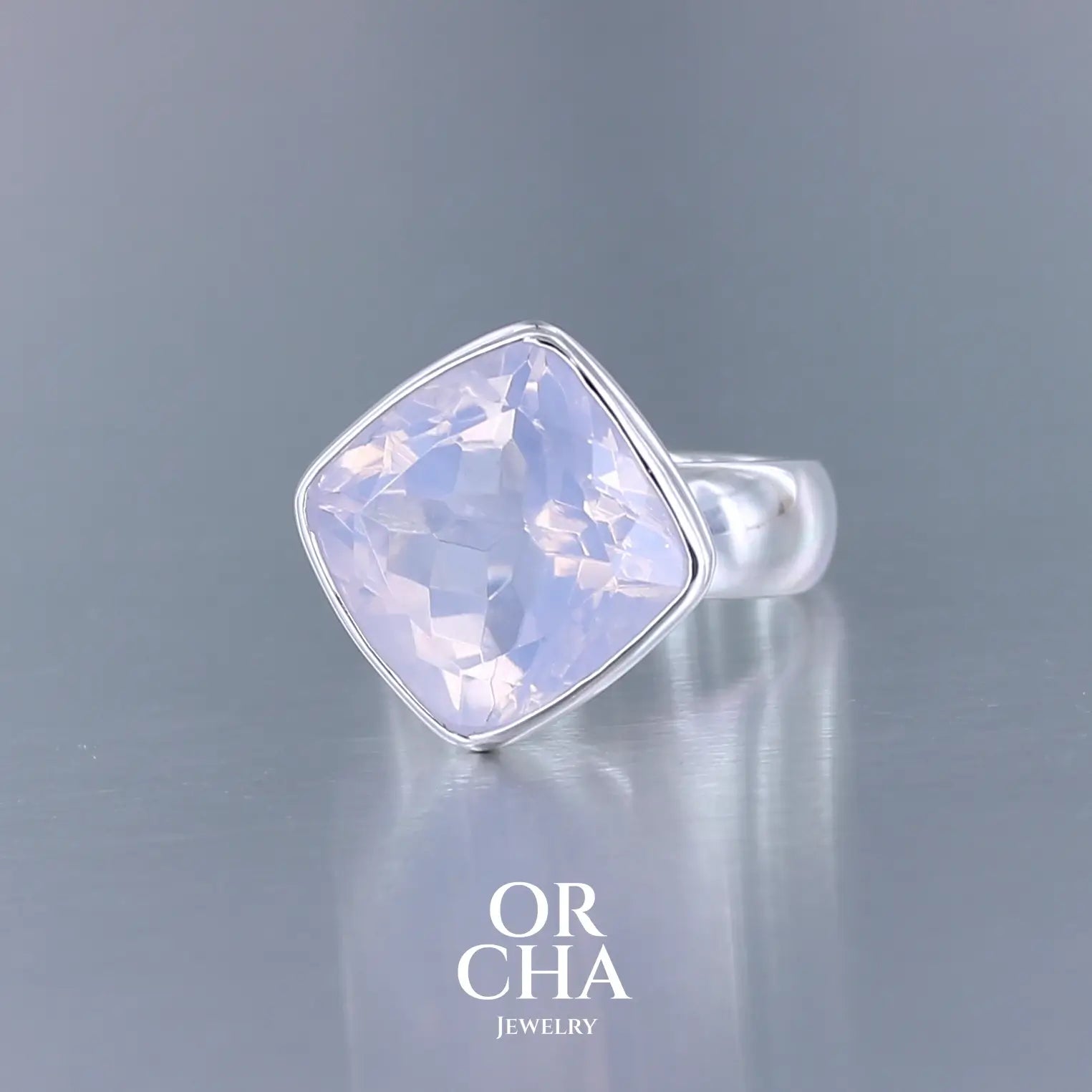 Bague cocktail pour femme en argent massif sertie d'un Quartz lavande. Pierre facettée de forme carrée de qualité transparente, propre à l'oeil. Pierre naturelle de couleur violette pastel teintée de rose avec de légers reflets opalescents. Plusieurs tailles disponibles. Bijoux unique, éthique et durable présenté dans un coffret de notre marque, prêt à offrir. Livraison offerte, certificat d'authenticité, service client.