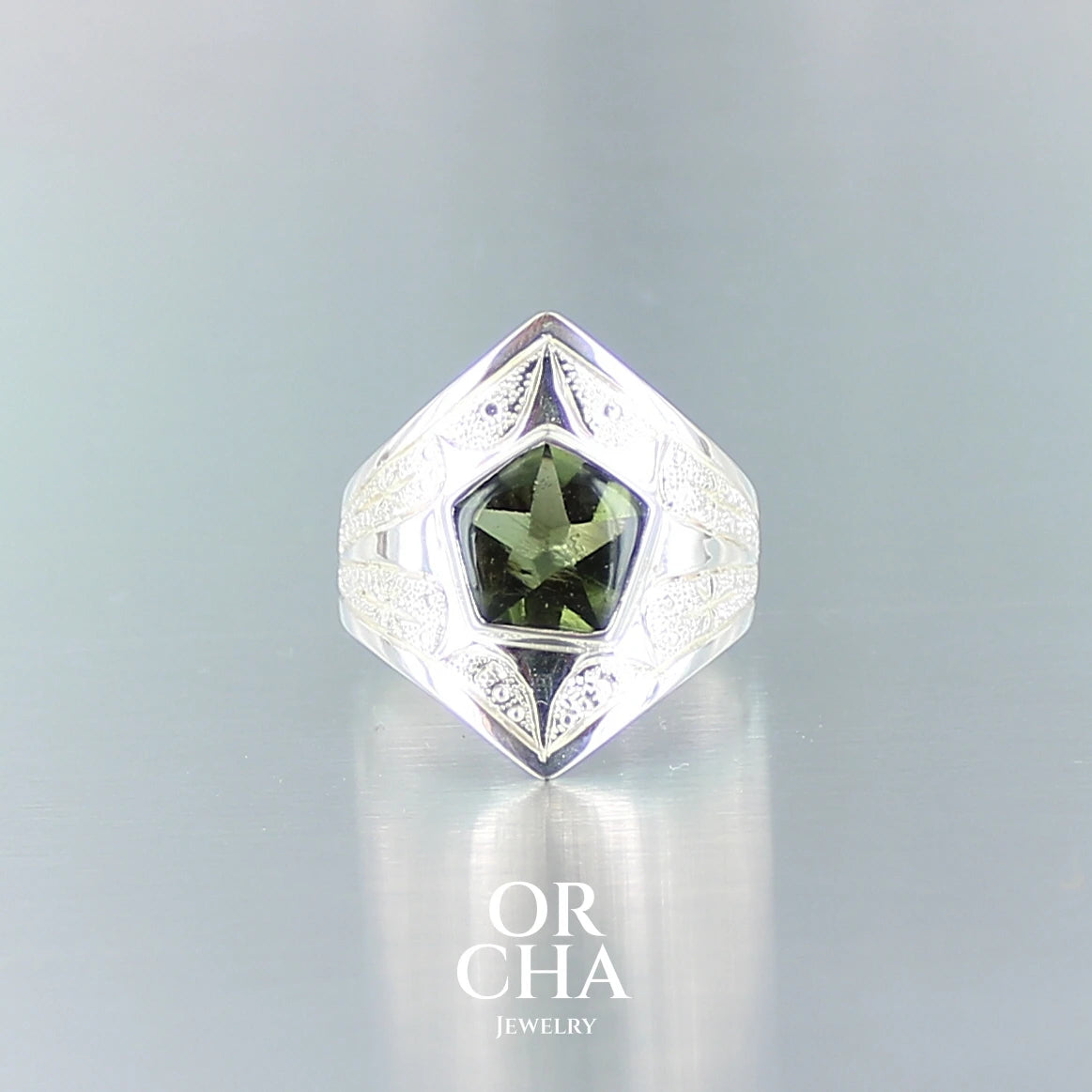 Bague pour femme en argent massif sculptées d'étoiles et autres corps célestes sertie d'un cabochon de Moldavite taillé en pentagramme dans laquelle se dessine une étoile . .Pierre naturelle transparente de couleur vert foncé . Taille 57. Bijoux unique, éthique et durable présenté dans un coffret de notre marque, prêt à offrir. Livraison offerte, certificat d'authenticité, service client.