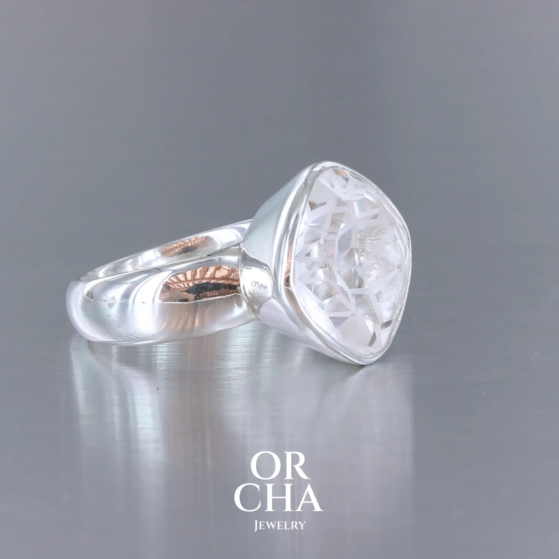 Bague cocktail pour femme en argent massif sertie d'un Cristal de roche gravé d'une fleur de vie. Pierre facettée de forme carrée de qualité transparente, propre à l'oeil. Pierre naturelle incolore et blanche sur les parties gravées. Bague réalisée en taille 60. Bijoux unique, éthique et durable présenté dans un coffret de notre marque, prêt à offrir. Livraison offerte, certificat d'authenticité, service client.