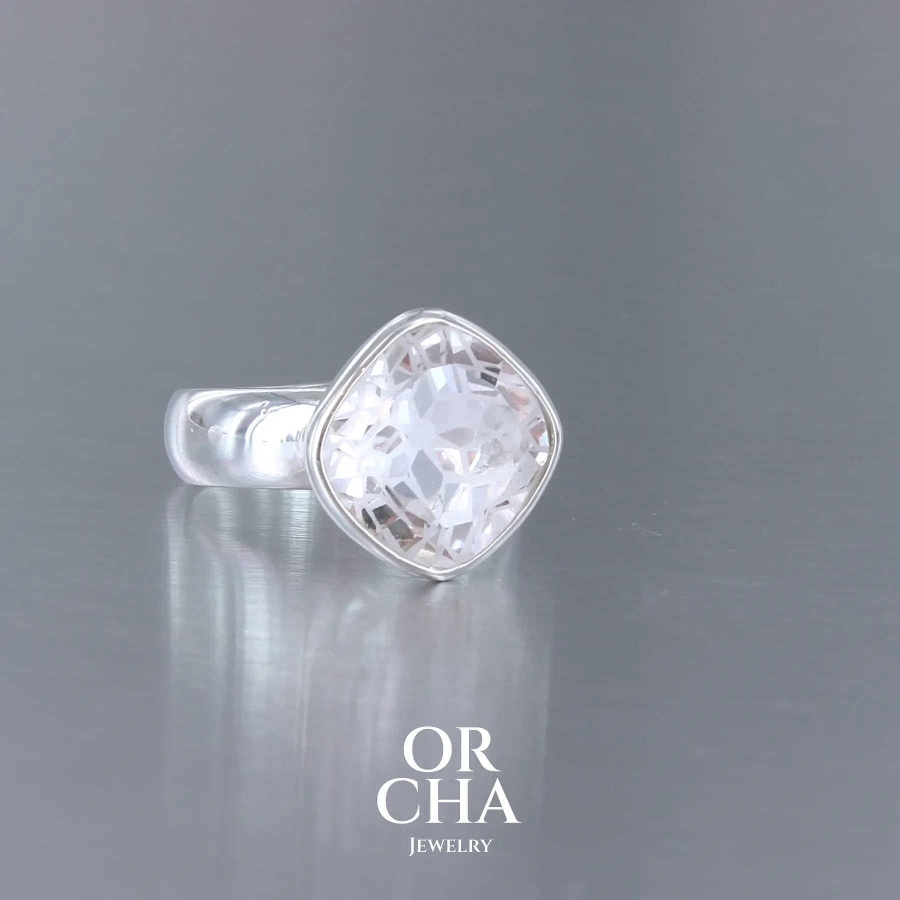 Bague cocktail pour femme en argent massif sertie d'un Cristal de roche gravé d'une fleur de vie. Pierre facettée de forme carrée de qualité transparente, propre à l'oeil. Pierre naturelle incolore et blanche sur les parties gravées. Bague réalisée en taille 52 ou 54. Bijoux unique, éthique et durable présenté dans un coffret de notre marque, prêt à offrir. Livraison offerte, certificat d'authenticité, service client.