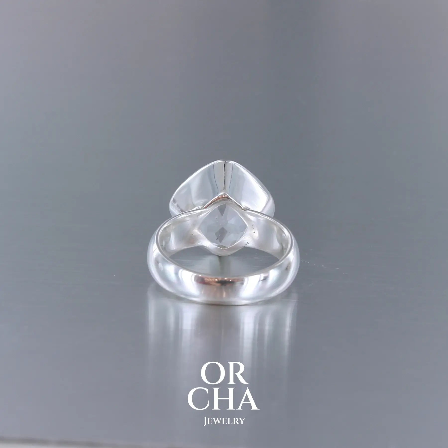 Bague cocktail pour femme en argent massif sertie d'un Cristal de roche gravé d'une fleur de vie. Pierre facettée de forme carrée de qualité transparente, propre à l'oeil. Pierre naturelle incolore et blanche sur les parties gravées. Bague réalisée en taille 52 ou 54. Bijoux unique, éthique et durable présenté dans un coffret de notre marque, prêt à offrir. Livraison offerte, certificat d'authenticité, service client.
