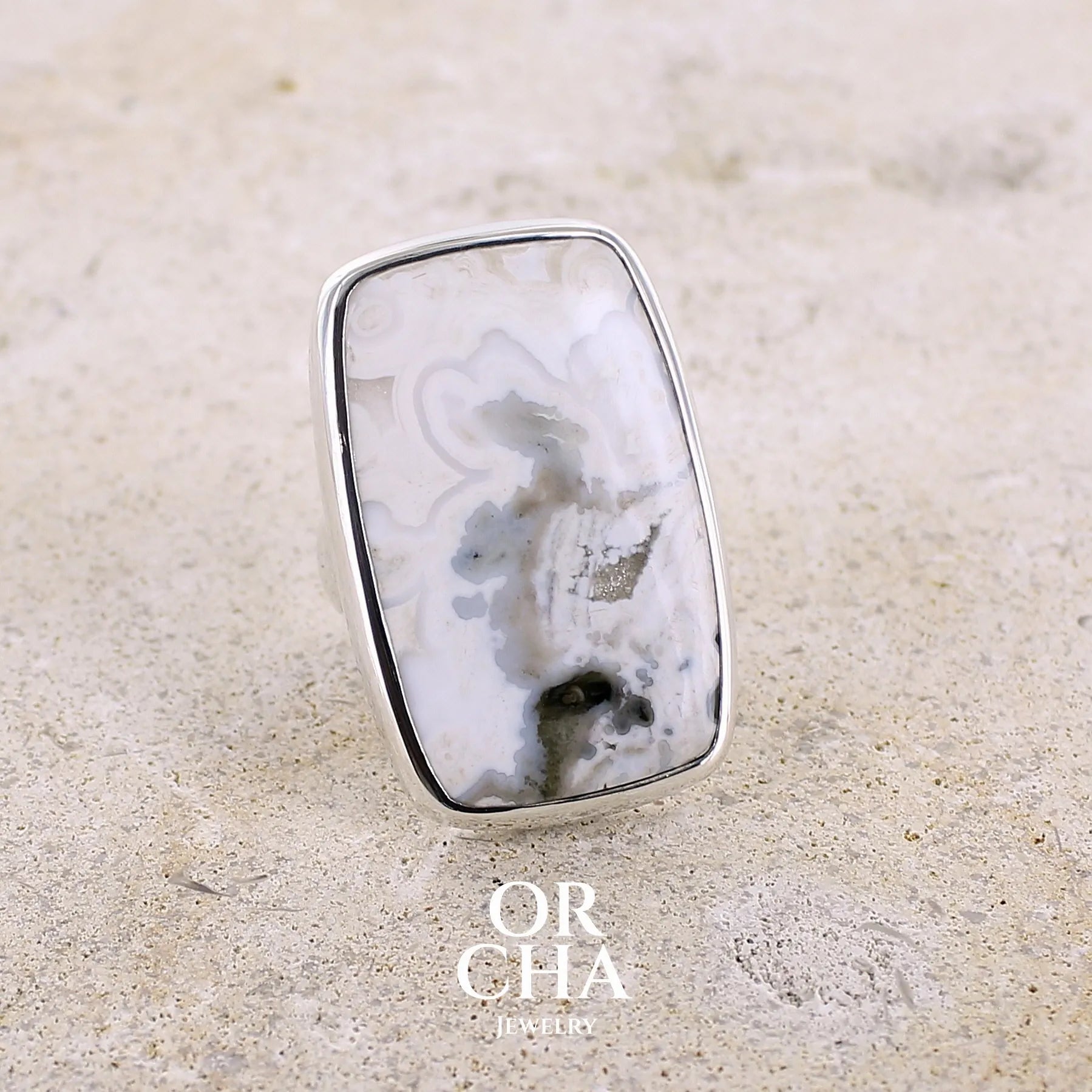 Bague pour femme en argent massif sertie d'un cabochon rectangulaire de jaspe océan de couleur blanc crème, gris, kaki et beige. Pierre de qualité opaque. Bijou unique réalisée en taille 54 par Orchajewelry