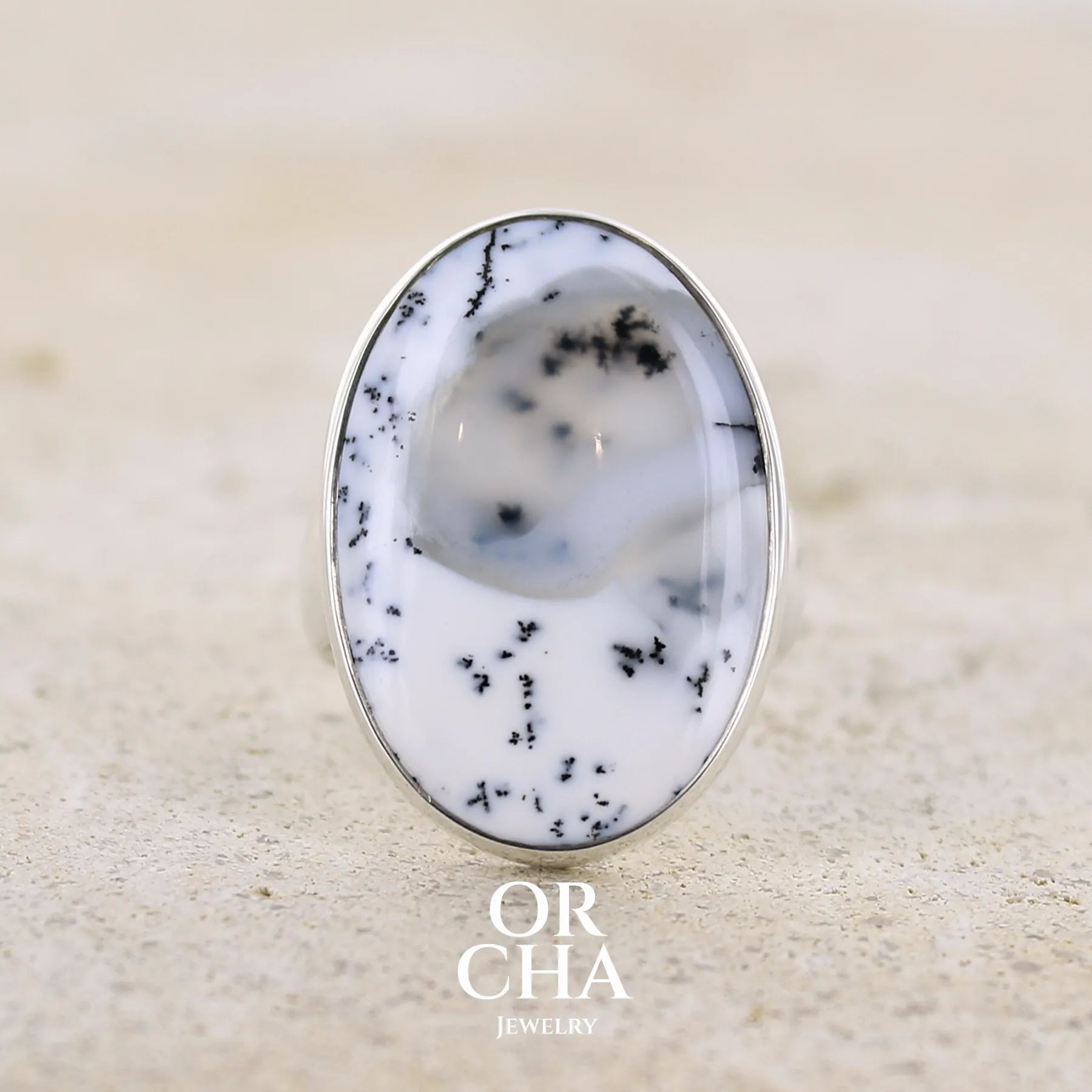 Bague pour femme en argent massif sertie d'un cabochon ovale d'agate dendritique de couleur blanc pur et noir. Pierre paysage opaque translucide à inclusions de dendrites de manganèse noires contrastées. Bijou unique réalisée en taille 52 par Orchajewelry