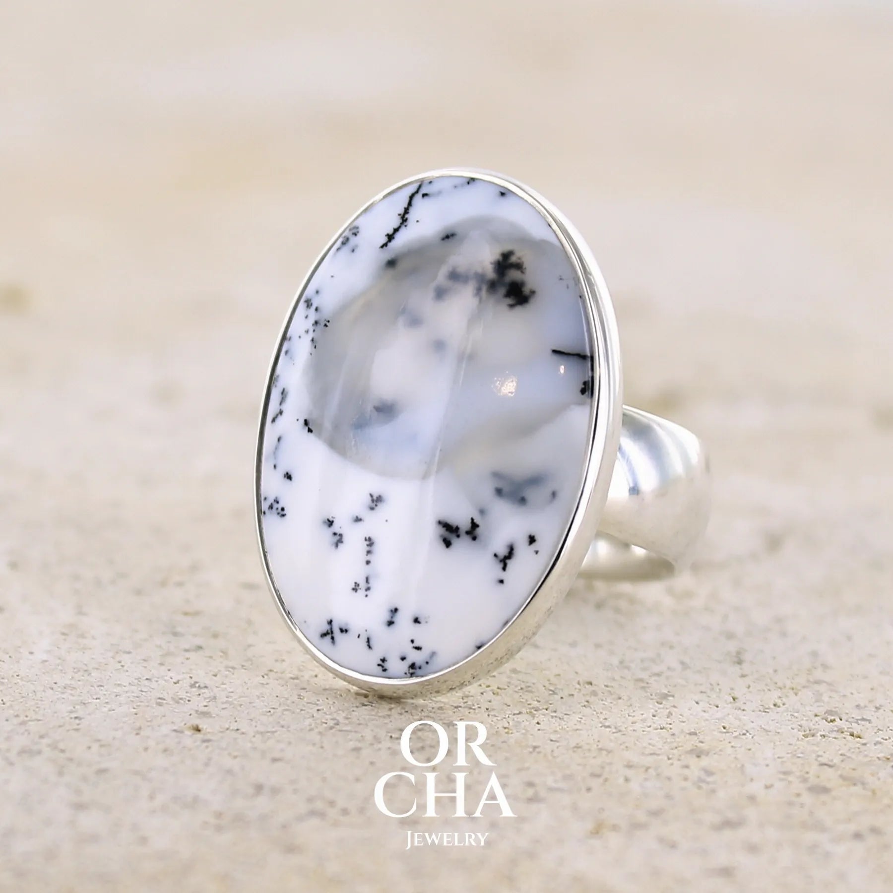 Bague pour femme en argent massif sertie d'un cabochon ovale d'agate dendritique de couleur blanc pur et noir. Pierre paysage opaque translucide à inclusions de dendrites de manganèse noires contrastées. Bijou unique réalisée en taille 52 par Orchajewelry