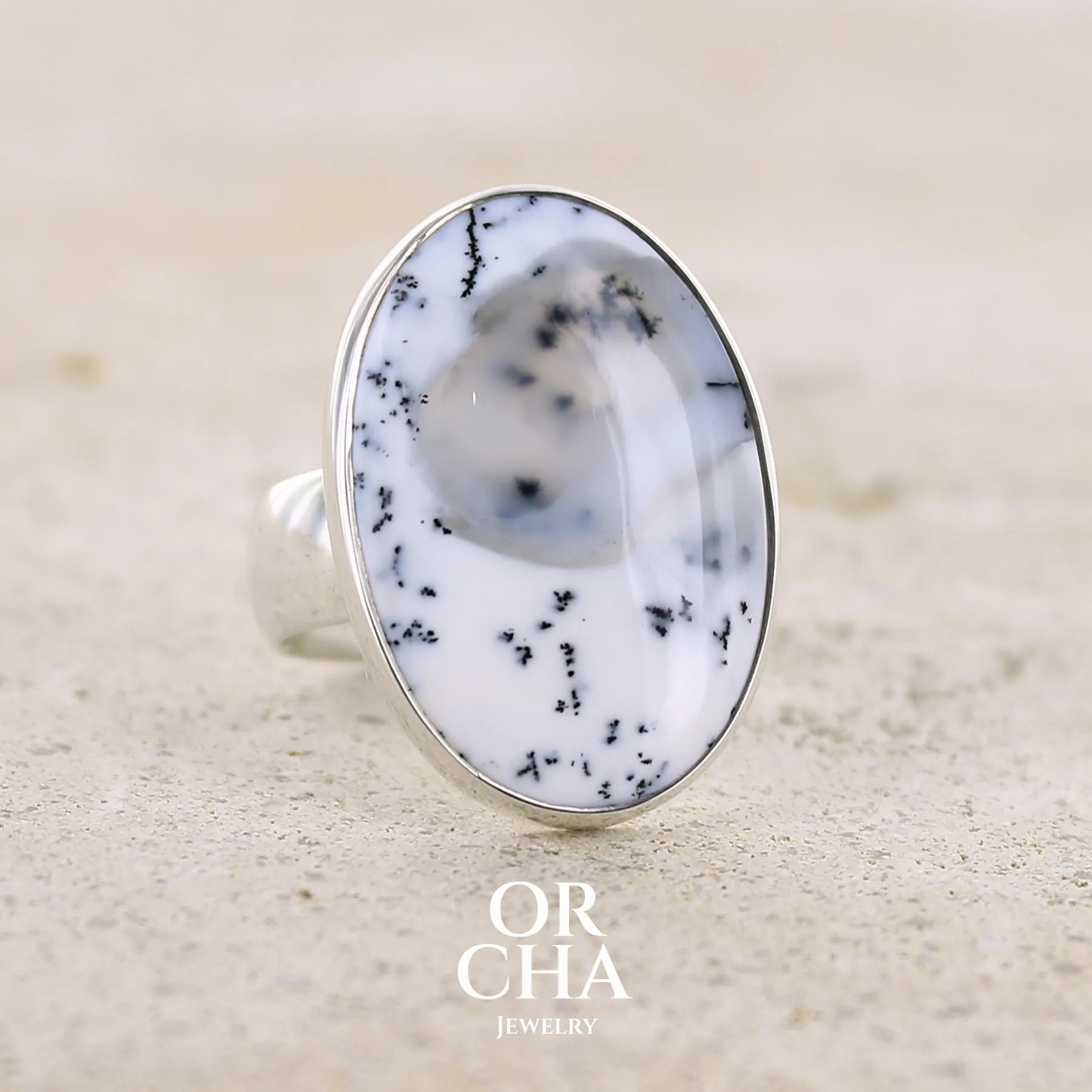 Bague pour femme en argent massif sertie d'un cabochon ovale d'agate dendritique de couleur blanc pur et noir. Pierre paysage opaque translucide à inclusions de dendrites de manganèse noires contrastées. Bijou unique réalisée en taille 52 par Orchajewelry
