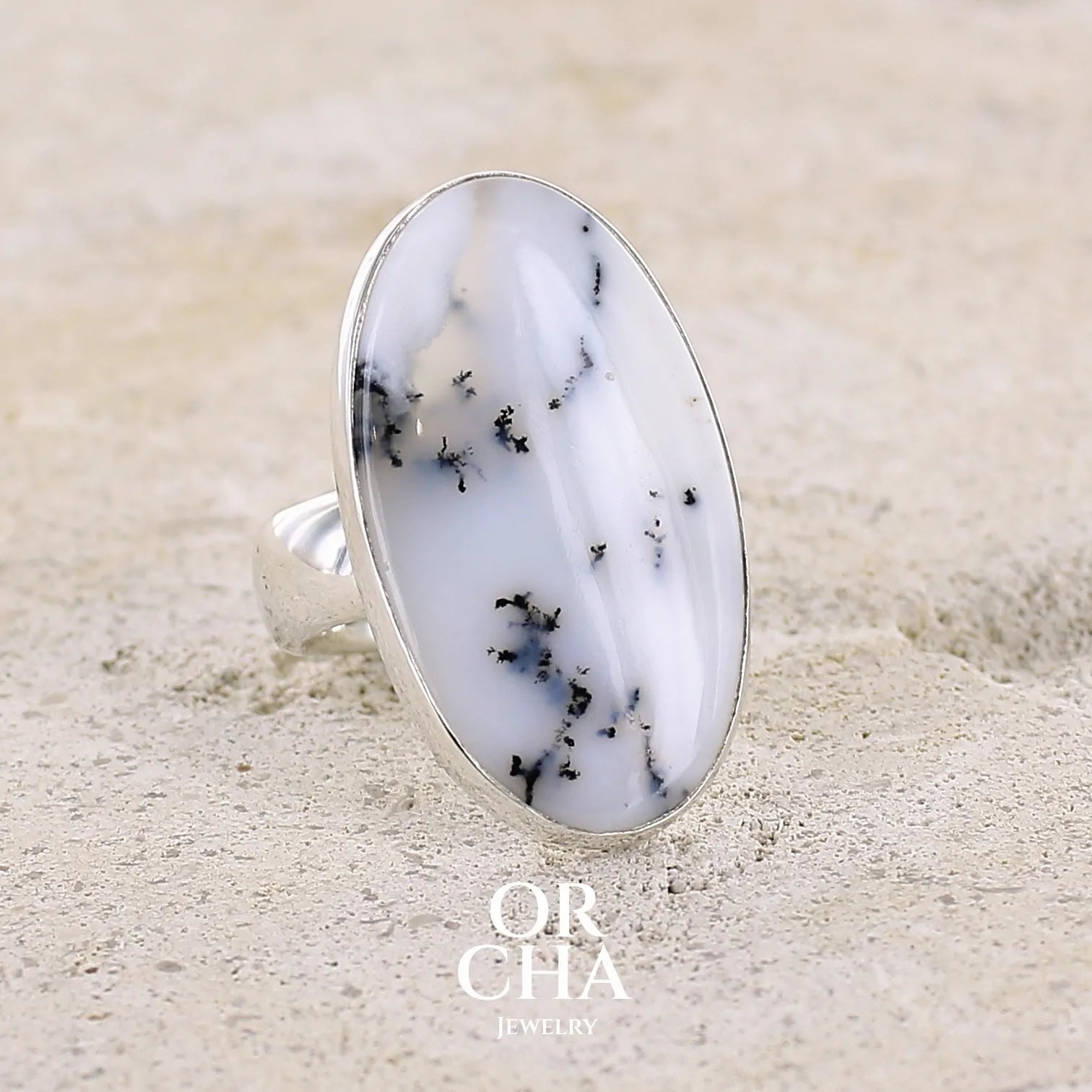 Bague pour femme en argent massif sertie d'un cabochon d'agate dendritique de couleur blanche et noire. Pierre de forme ovale de qualité translucide à inclusions paysages de manganèse contrastées. Bijou unique réalisée en taille 58,5 par Orcha Jewelry