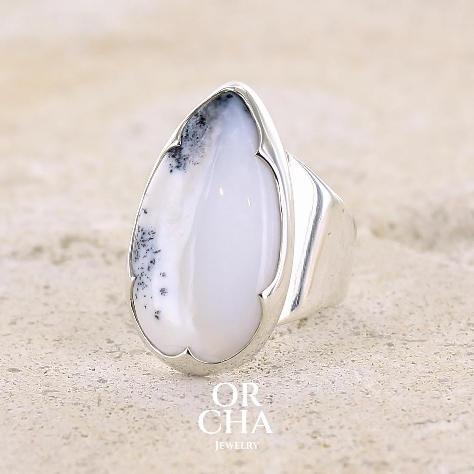 Bague pour femme en argent massif sertie d'un cabochon d'agate dendritique de couleur blanche et noire. Pierre translucide à inclusions paysages de manganèse contrastées. Bijou unique réalisée en taille 58 par Orcha Jewelry