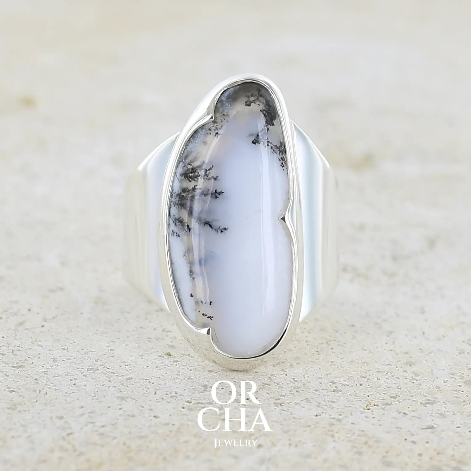 Bague pour femme en argent massif sertie d'un cabochon d'agate dendritique de couleur blanc pur et noir. Pierre opaque translucide à inclusions arborescentes de dendrites de manganèse noires contrastées. Bijou unique réalisée en taille 58 par Orchajewelry