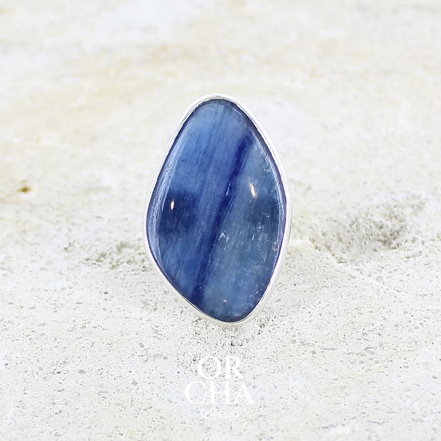 Bague pour femme en argent massif sertie d'un cabochon de cyanite de couleur bleu jean nacré. Pierre translucide à inclusions. Bijou unique réalisée en taille 54 par Orcha Jewelry