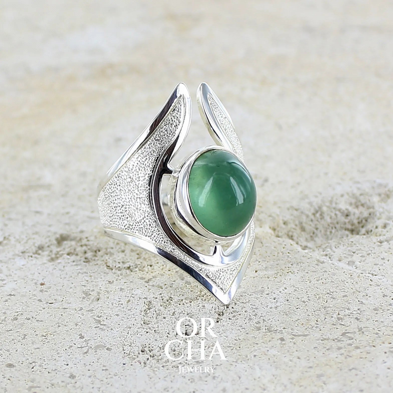 Grande bague pour femme en argent massif sertie d'une préhnite de couleur verte jaune clair, Pierre taillée en cabochon en forme de goutte. Pierre gemme de qualité transparente à inclusions. Bijoux unique réalisé en taille 59 par Orchajewelry.