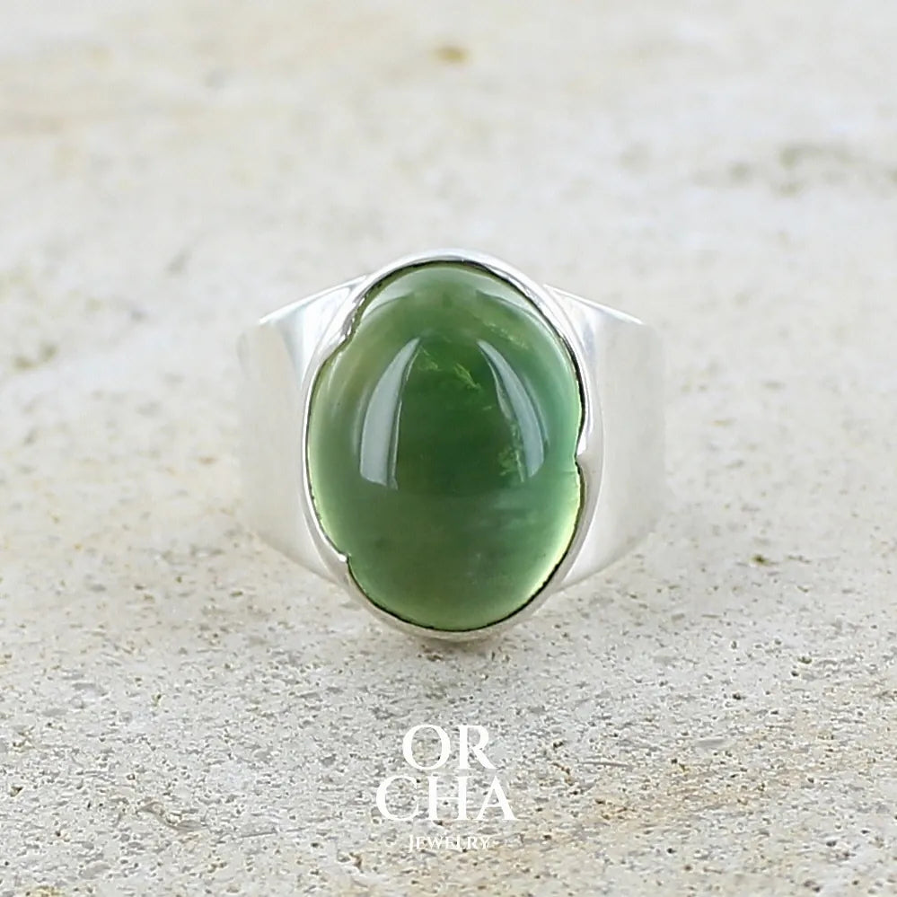 Bague pour femme en argent massif sertie d'une préhnite de couleur verte jaune clair. Pierre ovale taillée en cabochon. Pierre gemme de qualité transparente à inclusions. Bijoux unique réalisé en taille 52 par Orchajewelry.