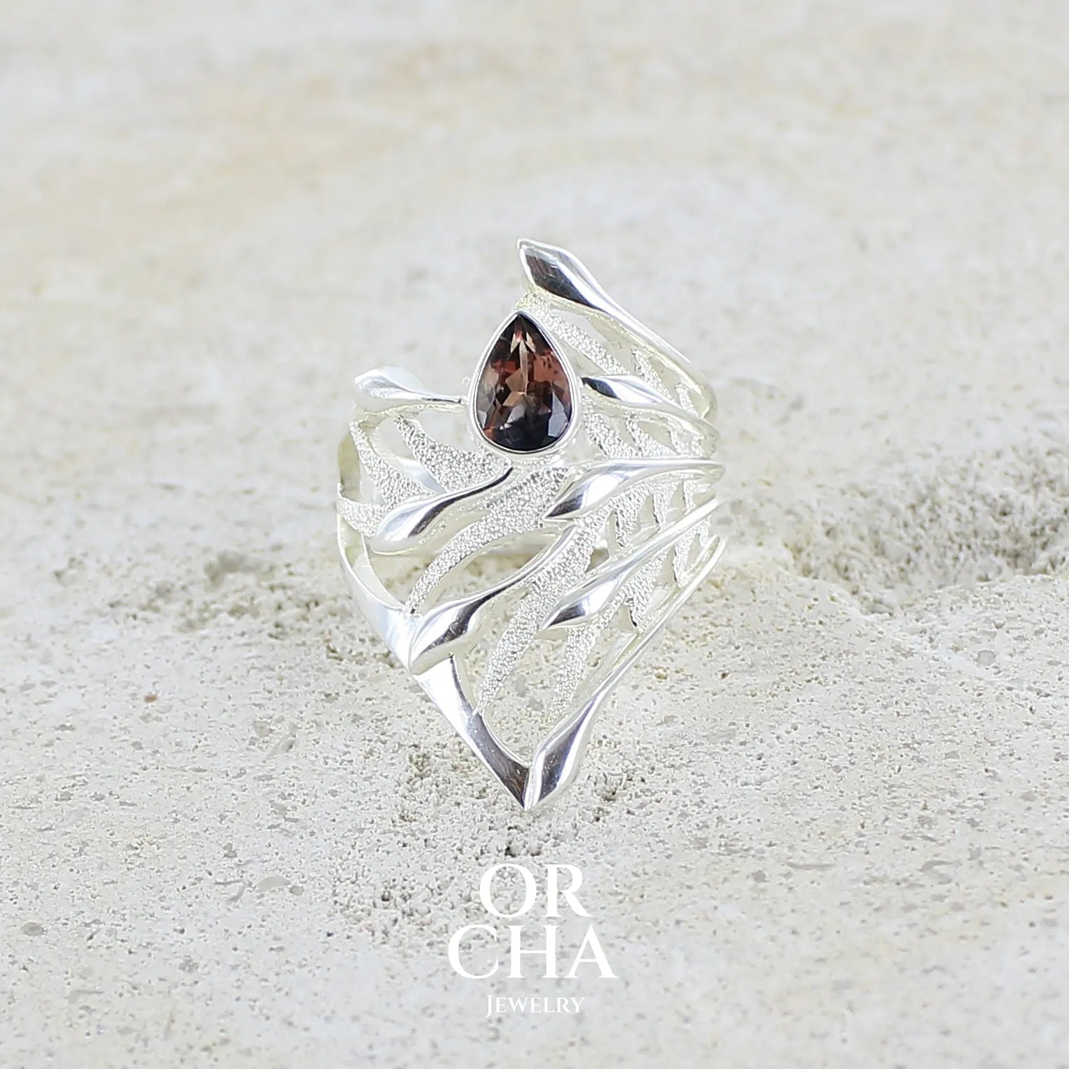 Grande Bague pour femme en argent massif, sertie d'une Tourmaline bicolore rose pêche et bleue nuit. Pierre facettée en forme de goutte. Pierre incolore, très lumineuse et propre à l'oeil. Bijoux unique au design de feuillage tropicale travaillé en filigrane réalisé en taille 54.