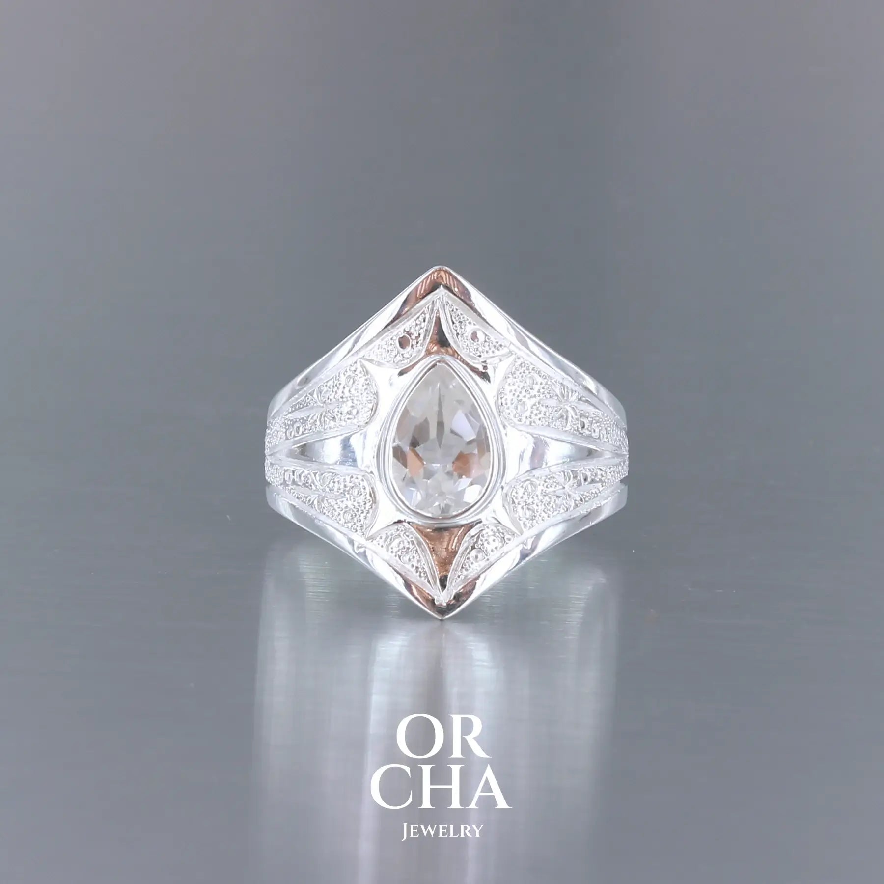 Bague pour femme en argent massif sculptées d'étoiles et autres corps célestes sertie d'une Topaze blanche.. Pierre facettée en forme de goutte, de couleur incolore, de qualité transparente ayant un très bel éclat. Disponible en plusieurs tailles. Bijoux unique, éthique et durable présenté dans un coffret de notre marque, prêt à offrir. Livraison offerte, certificat d'authenticité, service client.
