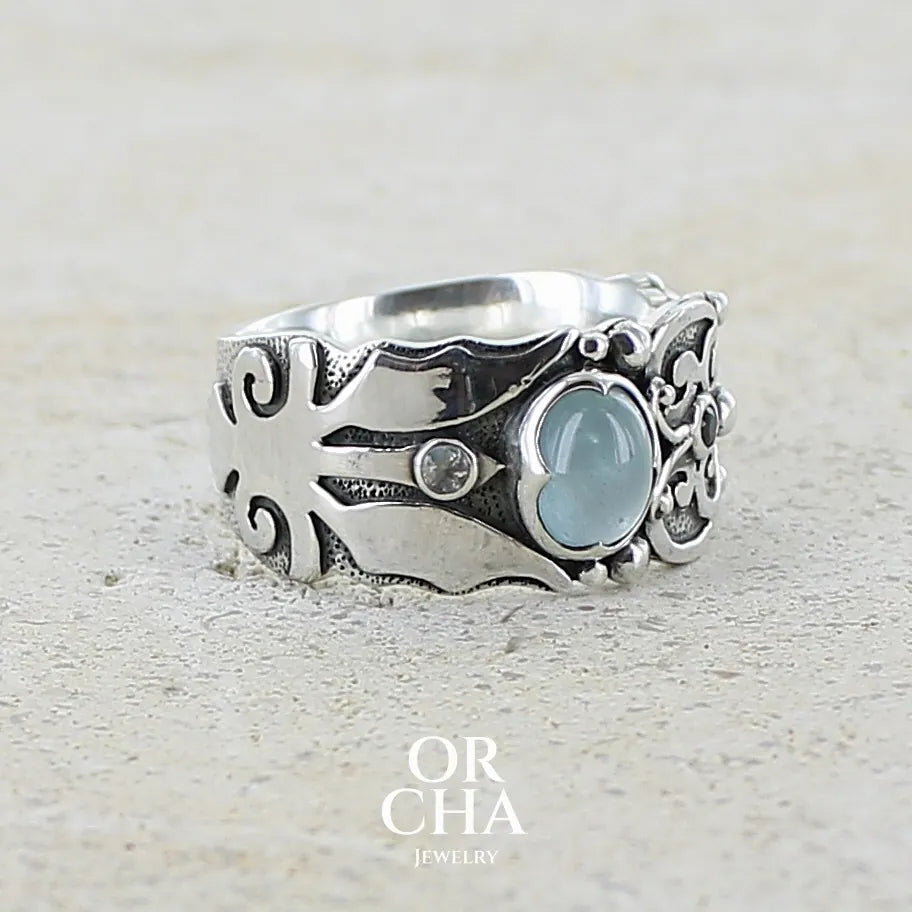 Bague anneau pour homme en argent massif d'inspiration celtique, médiévale. Bague sertie d'un cabochon d'aigue-marine de couleur bleu gris. Pierre translucide propre à l'oeil. Bijou unique réalisé en taille 58.