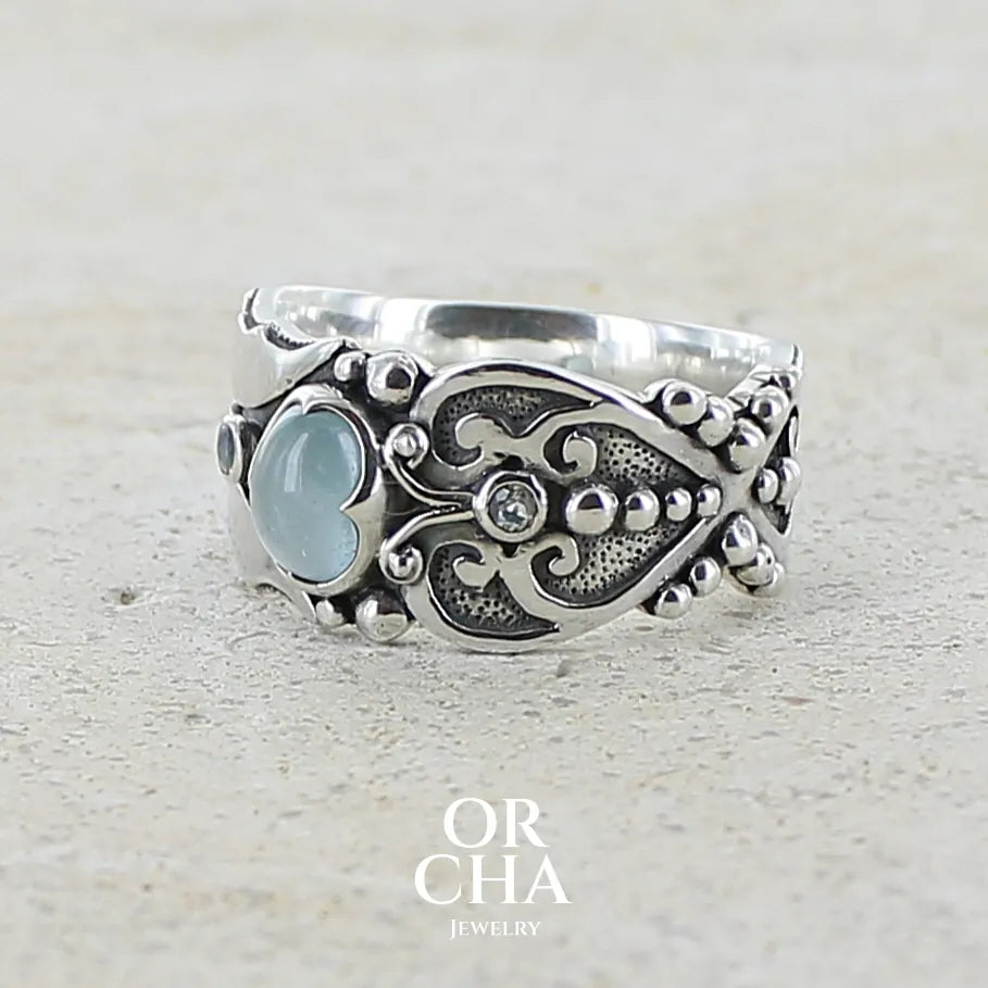 Bague anneau pour homme en argent massif d'inspiration celtique, médiévale. Bague sertie d'un cabochon d'aigue-marine de couleur bleu gris. Pierre translucide propre à l'oeil. Bijou unique réalisé en taille 58.