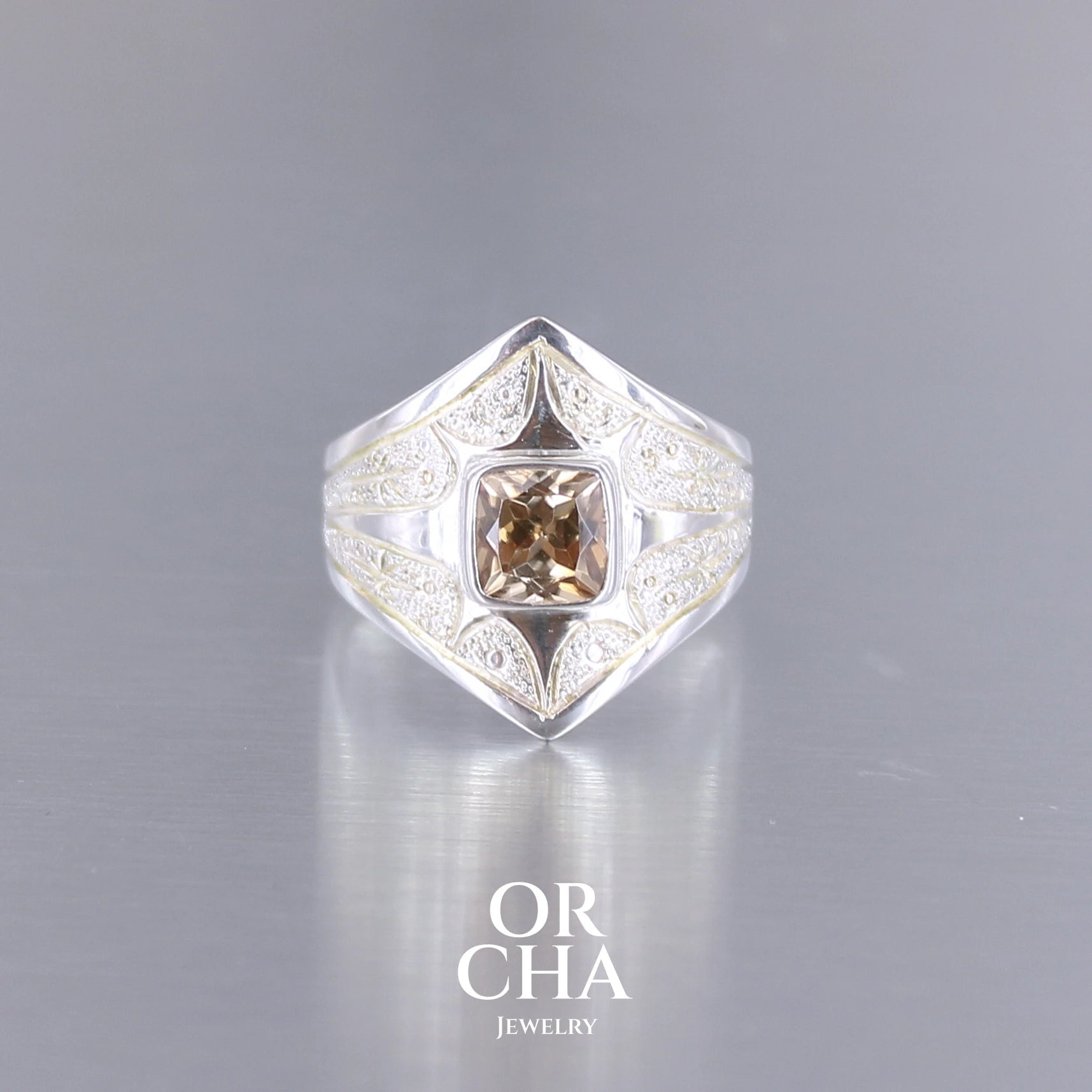 Bague pour femme en argent massif sculptées d'étoiles et autres corps célestes sertie d'une Topaze dorée aux nuances colorées de dorées à bruns. Pierre naturelle, facettée de forme carrée, de qualité transparente présentant un très bel éclat. Taille 55. Bijoux unique, éthique et durable présenté dans un coffret de notre marque, prêt à offrir. Livraison offerte, certificat d'authenticité, service client.