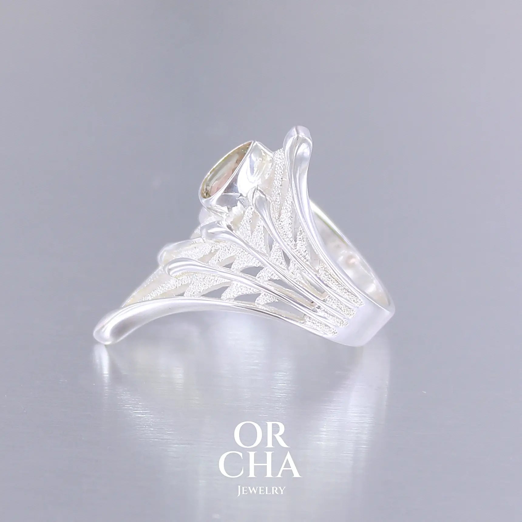 Profil d'une grande Bague pour femme, feuillage tropicale travaillé en filigrane en argent massif, sertie d'une Tourmaline bicolore rose pêche et verte kaki. Pierre facettée en forme de goutte. Pierre incolore, très lumineuse et propre à l'oeil. Taille 56. Bijoux unique, éthique et durable présenté dans un coffret de notre marque, prêt à offrir. Livraison offerte, certificat d'authenticité, service client.