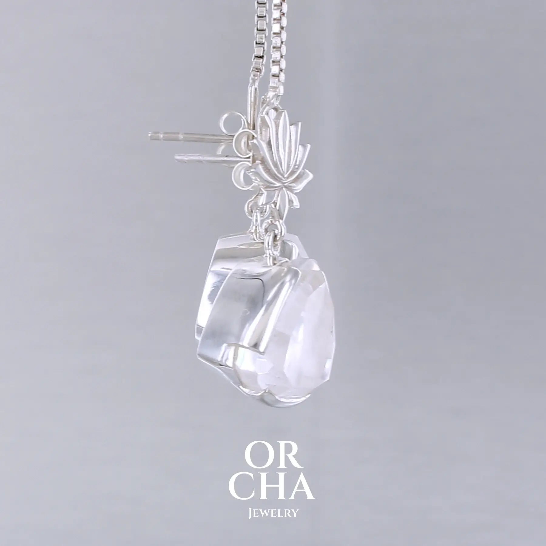 Boucles d'oreilles pour femme en argent massif sertie de Cristals de roche gravés de fleurs de vie. Pierres facettées de forme triangulaire de qualités transparentes, propre à l'oeil. Pierre naturelle incolore et blanche sur les parties gravées. Le clou des boucles représente un lotus. Bijoux unique, éthique et durable présenté dans un coffret de notre marque, prêt à offrir. Livraison offerte, certificat d'authenticité, service client.