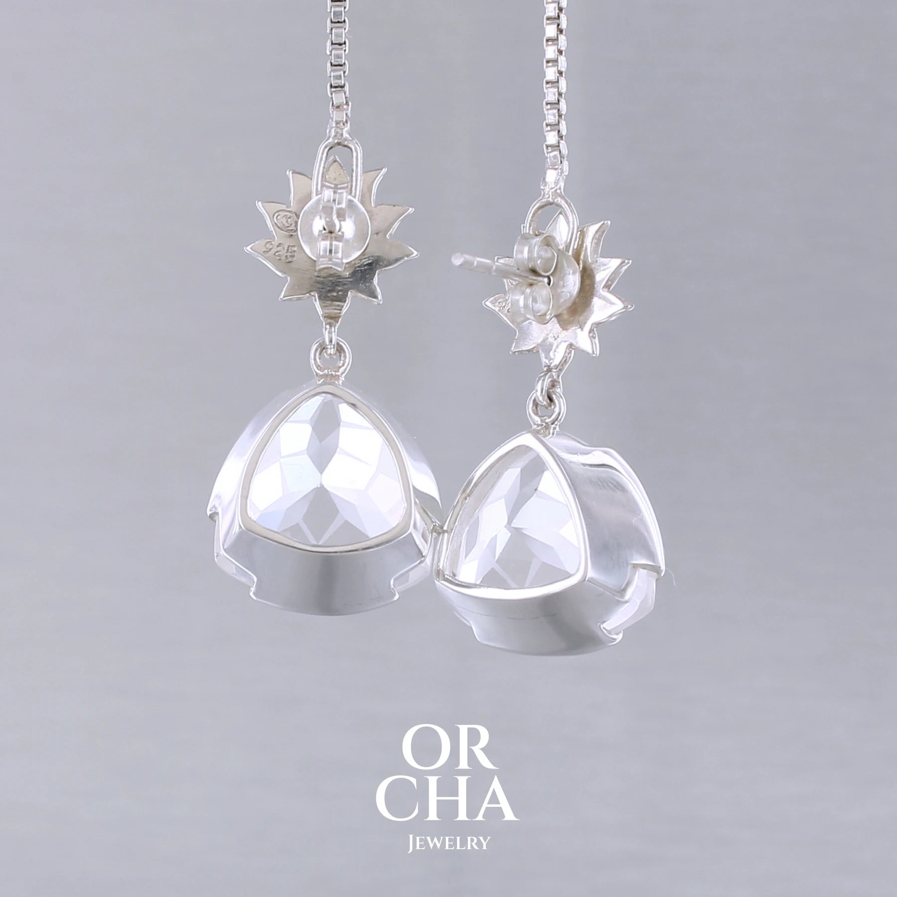 Boucles d'oreilles pour femme en argent massif sertie de Cristals de roche gravés de fleurs de vie. Pierres facettées de forme triangulaire de qualités transparentes, propre à l'oeil. Pierre naturelle incolore et blanche sur les parties gravées. Le clou des boucles représente un lotus. Bijoux unique, éthique et durable présenté dans un coffret de notre marque, prêt à offrir. Livraison offerte, certificat d'authenticité, service client.