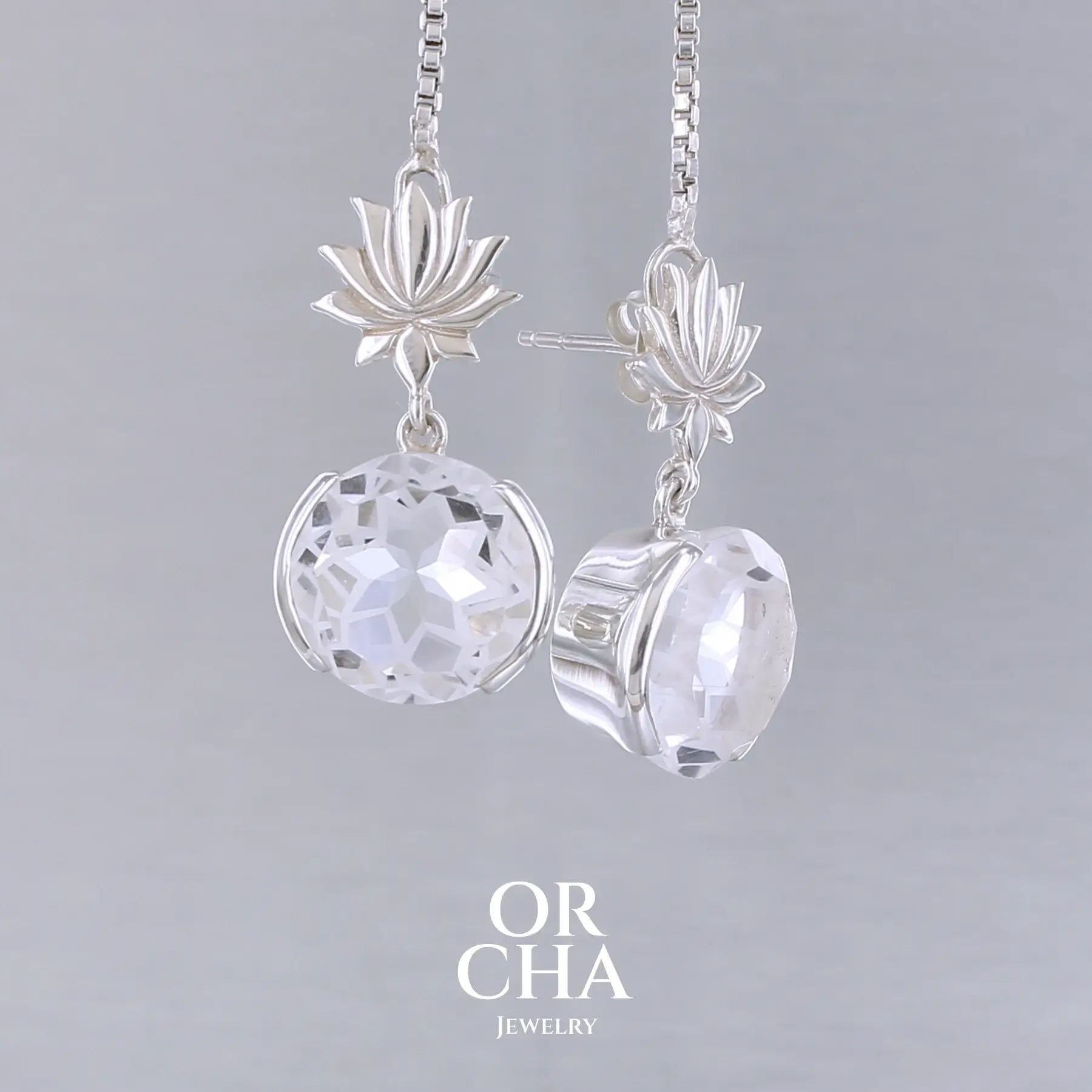 Boucles d'oreilles pour femme en argent massif sertie de Cristals de roche gravés de fleurs de vie. Pierres facettées de forme ronde de qualités transparentes, propre à l'oeil. Pierre naturelle incolore et blanche sur les parties gravées. Le clou des boucles représente un lotus. Bijoux unique, éthique et durable présenté dans un coffret de notre marque, prêt à offrir. Livraison offerte, certificat d'authenticité, service client.