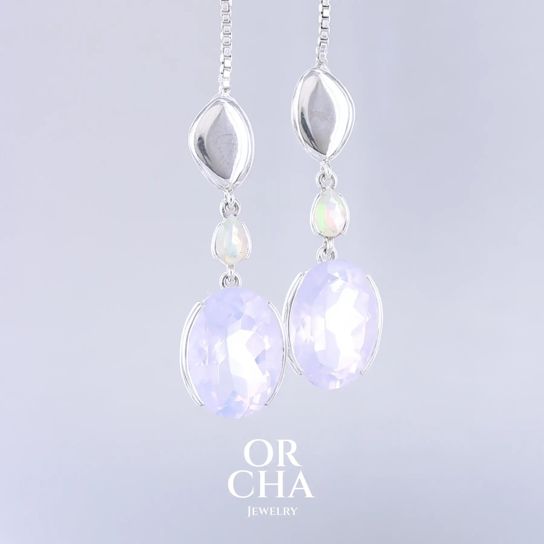 Boucles d'oreilles pour femme en argent massif sertie de Quartz lavandes et d'opales d'Éthiopie. Pierres facettées de forme ovales et de gouttes de qualités transparentes, propre à l'oeil. Pierres naturelles de couleurs violettes pastel teintées de rose avec des reflets opalescents et multicolores pour les opales . Bijoux unique, éthique et durable présenté dans un coffret de notre marque, prêt à offrir. Livraison offerte, certificat d'authenticité, service client.