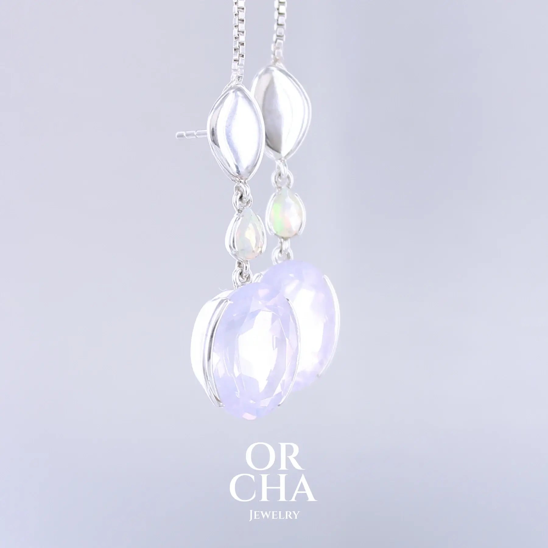 Boucles d'oreilles pour femme en argent massif sertie de Quartz lavandes et d'opales d'Éthiopie. Pierres facettées de forme ovales et de gouttes de qualités transparentes, propre à l'oeil. Pierres naturelles de couleurs violettes pastel teintées de rose avec des reflets opalescents et multicolores pour les opales . Bijoux unique, éthique et durable présenté dans un coffret de notre marque, prêt à offrir. Livraison offerte, certificat d'authenticité, service client.