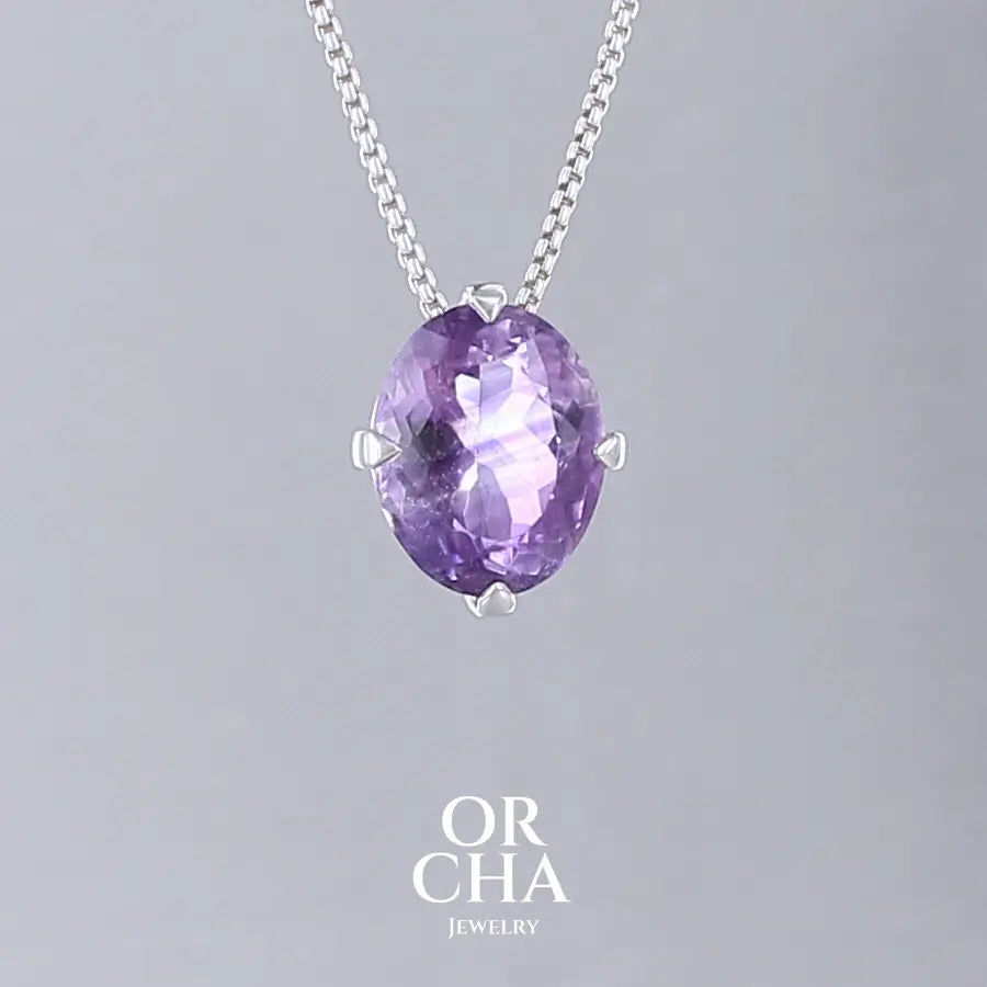 Collier solitaire pour femme en argent massif sertie d'une Améthyste. Pierre facettée de forme ovale de qualité transparente, inclusions. Pierre naturelle de couleur violet clair type rose de France. Pendentif monté sur une chaine en argent sterling de type maille vénitienne de 1,3 mm d'épaisseur et de 40 cm de longueur. Bijoux unique, éthique et durable présenté dans un coffret de notre marque, prêt à offrir. Livraison offerte, certificat d'authenticité, service client.