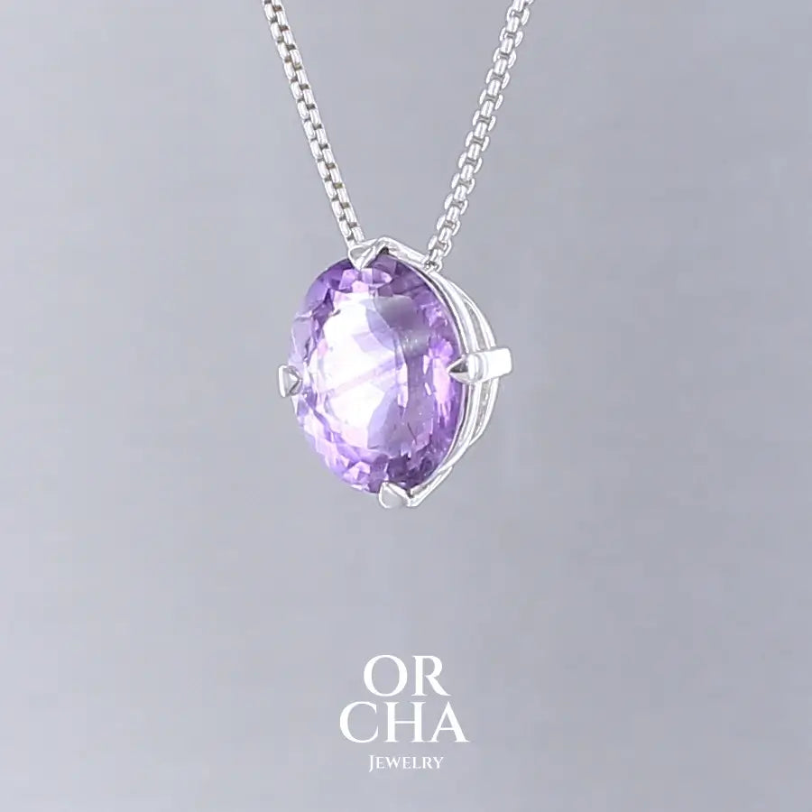 Collier solitaire pour femme en argent massif sertie d'une Améthyste. Pierre facettée de forme ovale de qualité transparente, inclusions. Pierre naturelle de couleur violet clair type rose de France. Pendentif monté sur une chaine en argent sterling de type maille vénitienne de 1,3 mm d'épaisseur et de 40 cm de longueur. Bijoux unique, éthique et durable présenté dans un coffret de notre marque, prêt à offrir. Livraison offerte, certificat d'authenticité, service client.