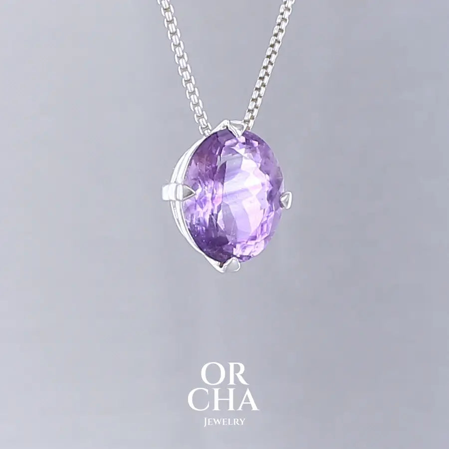 Collier solitaire pour femme en argent massif sertie d'une Améthyste. Pierre facettée de forme ovale de qualité transparente, inclusions. Pierre naturelle de couleur violet clair type rose de France. Pendentif monté sur une chaine en argent sterling de type maille vénitienne de 1,3 mm d'épaisseur et de 40 cm de longueur. Bijoux unique, éthique et durable présenté dans un coffret de notre marque, prêt à offrir. Livraison offerte, certificat d'authenticité, service client.