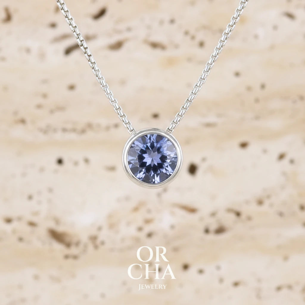 Collier solitaire pour femme en argent massif sertie d'une Tanzanite. Pierre facettée de forme ronde de qualité transparente, propre à l'oeil. Pierre naturelle de couleur bleu lavande avec de légers reflets verts. Pendentif monté sur une chaine en argent sterling de type maille vénitienne de 1,3 mm d'épaisseur et de 45 cm de longueur. Bijoux unique, éthique et durable présenté dans un coffret de notre marque, prêt à offrir. Livraison offerte, certificat d'authenticité, service client.