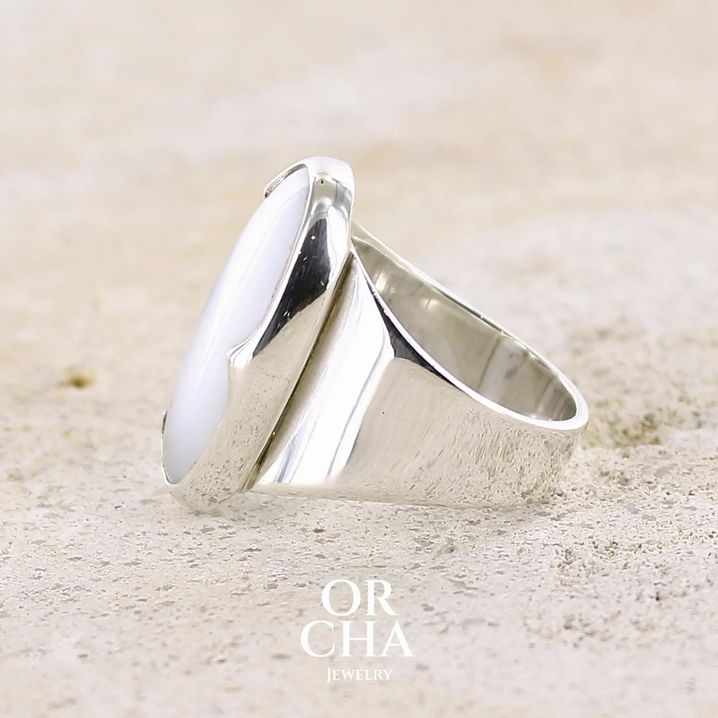 Détail du sertissage d'une bague pour femme en argent massif sertie d'un cabochon d'agate dendritique de couleur blanche et noire. Pierre de forme ovale de qualité translucide à inclusions paysages de manganèse contrastées. Bijou unique réalisée en taille 58 par Orcha Jewelry
