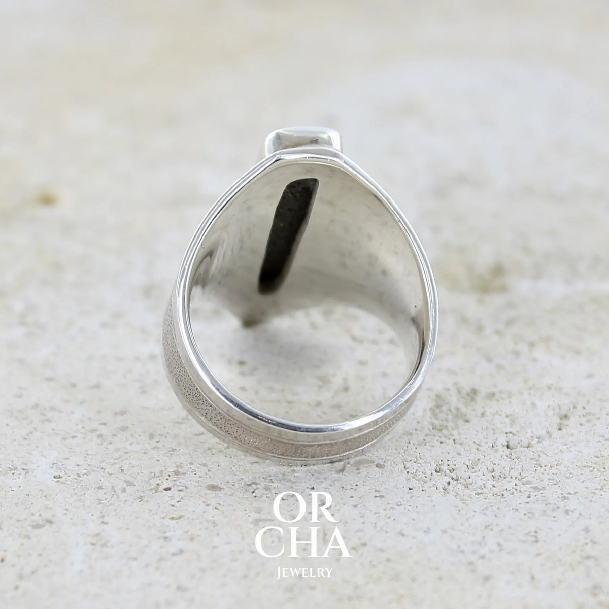 Vue de dos d'une bague pour femme en argent massif 925 sertie d'une opale boulder aux feux multicolores. Cabochon d'opale massive naturelle taillée en forme de rectangle.. Pierre de qualité opaque. Bague unique réalisée en taille 55 par Orcha Jewelry.
