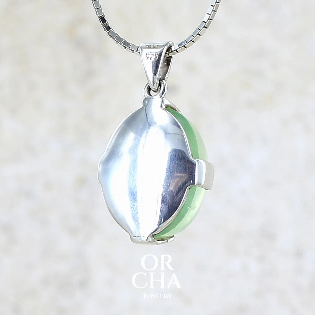 Vue de dos d'un Pendentif ovale en argent massif, serti d'un cabochon de préhnite de couleur verte clair. Pierre de qualité translucide comportant des inclusions. Bijoux unique par Orcha Jewelry