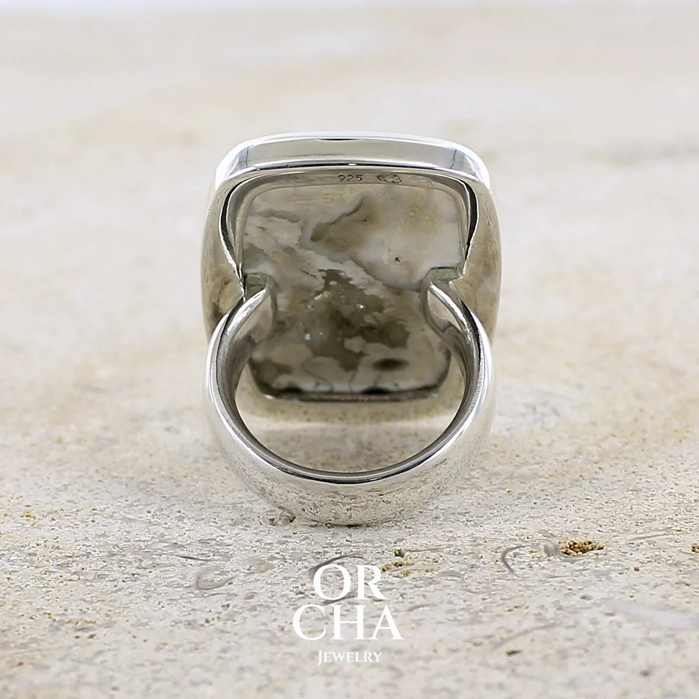 Vue de dos d'une bague pour femme en argent massif sertie d'un cabochon rectangulaire de jaspe océan de couleur blanc crème, gris, kaki et beige. Pierre de qualité opaque. Bijou unique réalisée en taille 54 par Orchajewelry