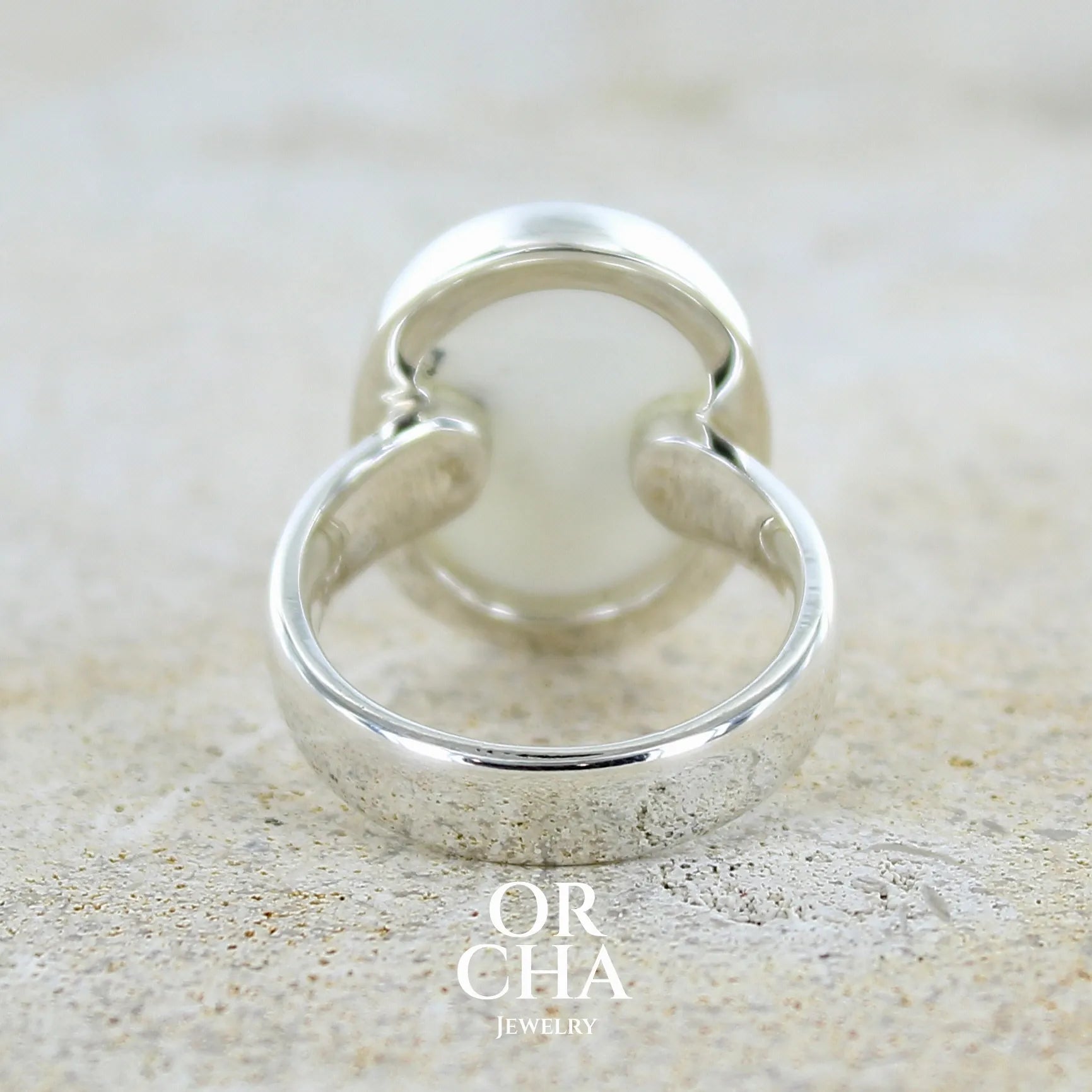 Vue de dos d'une bague pour femme en argent massif sertie d'un cabochon ovale d'agate dendritique de couleur blanc pur et noir. Pierre opaque à inclusions paysages de dendrites de manganèse noires contrastées. Bijou unique réalisée en taille 54 par Orchajewelry