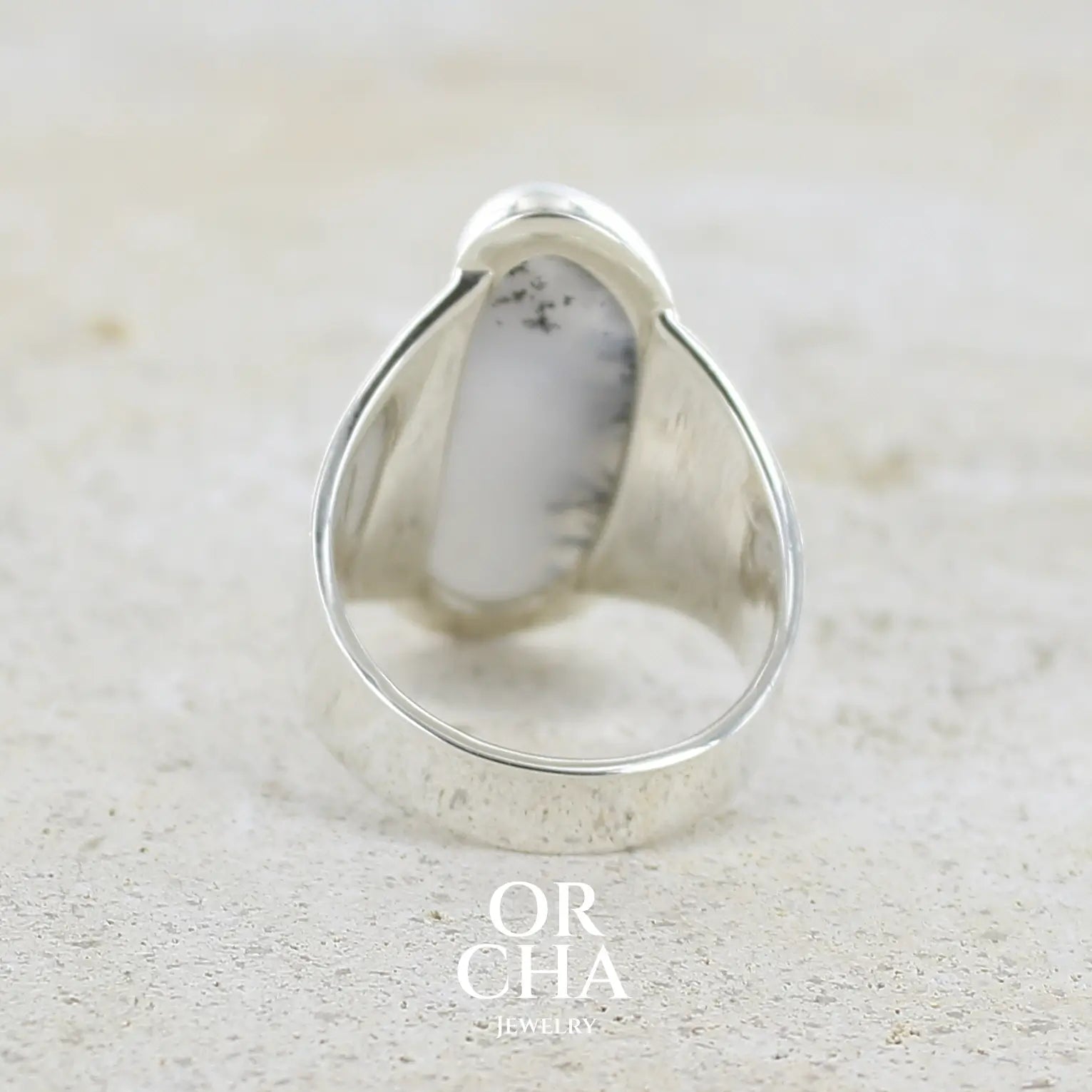 Vue de dos d'une Bague pour femme en argent massif sertie d'un cabochon d'agate dendritique de couleur blanc pur et noir. Pierre opaque translucide à inclusions arborescentes de dendrites de manganèse noires contrastées. Bijou unique réalisée en taille 58 par Orchajewelry