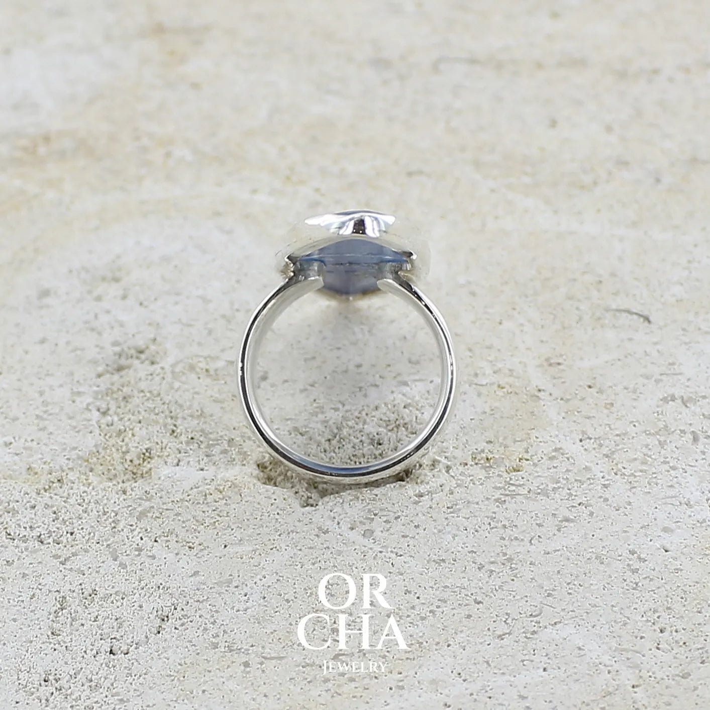 Vue de dos d'une bague marquise pour femme en argent massif sertie d'un cabochon de cyanite de couleur bleu jean nacré. Pierre translucide à inclusions. Bijou unique réalisée en taille 58 par Orchajewelry