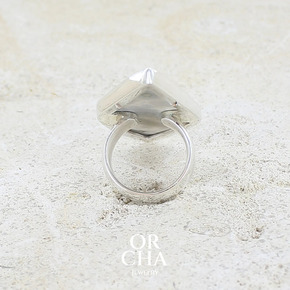 Vue de dos d'une grande bague pour femme en argent massif sertie d'un cabochon de jaspe orbiculaire de couleur crème, kaki et gris. Pierre naturelle de qualité opaque taillée en forme de losange, Bijou unique réalise en taille 56 par Orcha Jewelry