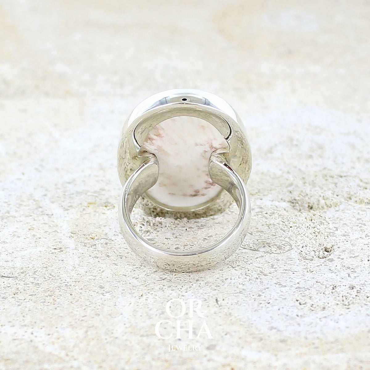 Vue de dos d'une bague pour femme en argent massif sertie d'un cabochon de scolecite de couleur blanc pur. Pierre naturelle de qualité opaque taillée en ovale. Bague unique réalisée en taille 58 par Orcha jewelry