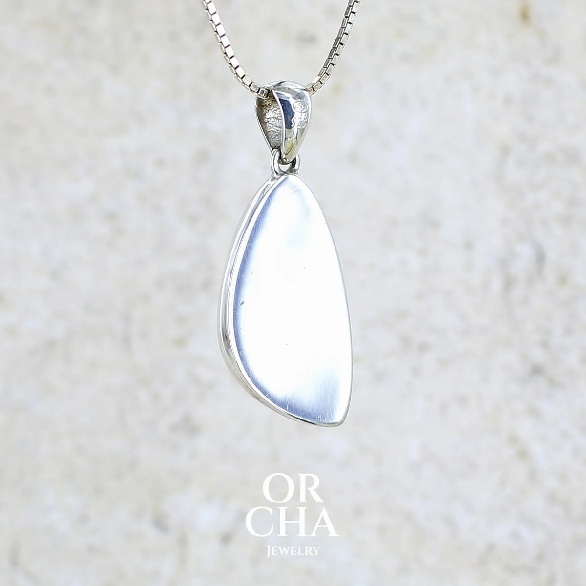 Vue de dos d'un pendentif pour femme en argent massif sertie d'un cabochon en forme d'aile d'agate dendritique de couleur blanc pur et noir. Pierre opaque à translucide à inclusions paysages de dendrites de manganèse noires contrastées. Bijou unique réalisé par Orchajewelry