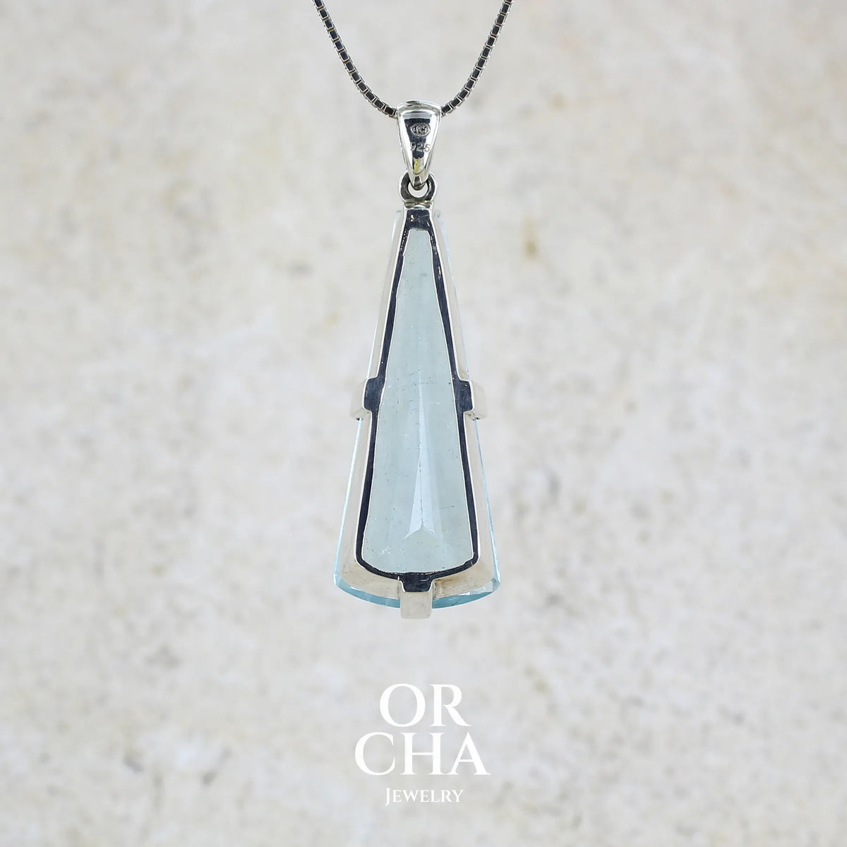 Vue de dos d'un Pendentif en argent massif sertie d'une aigue marine taillée de 32 carats de couleur bleu clair profond et lumineux, pierre transparente avec inclusions. Pierre naturelle facettée de forme triangulaire allongé. Bijoux unique réalisée par Orchajewelry