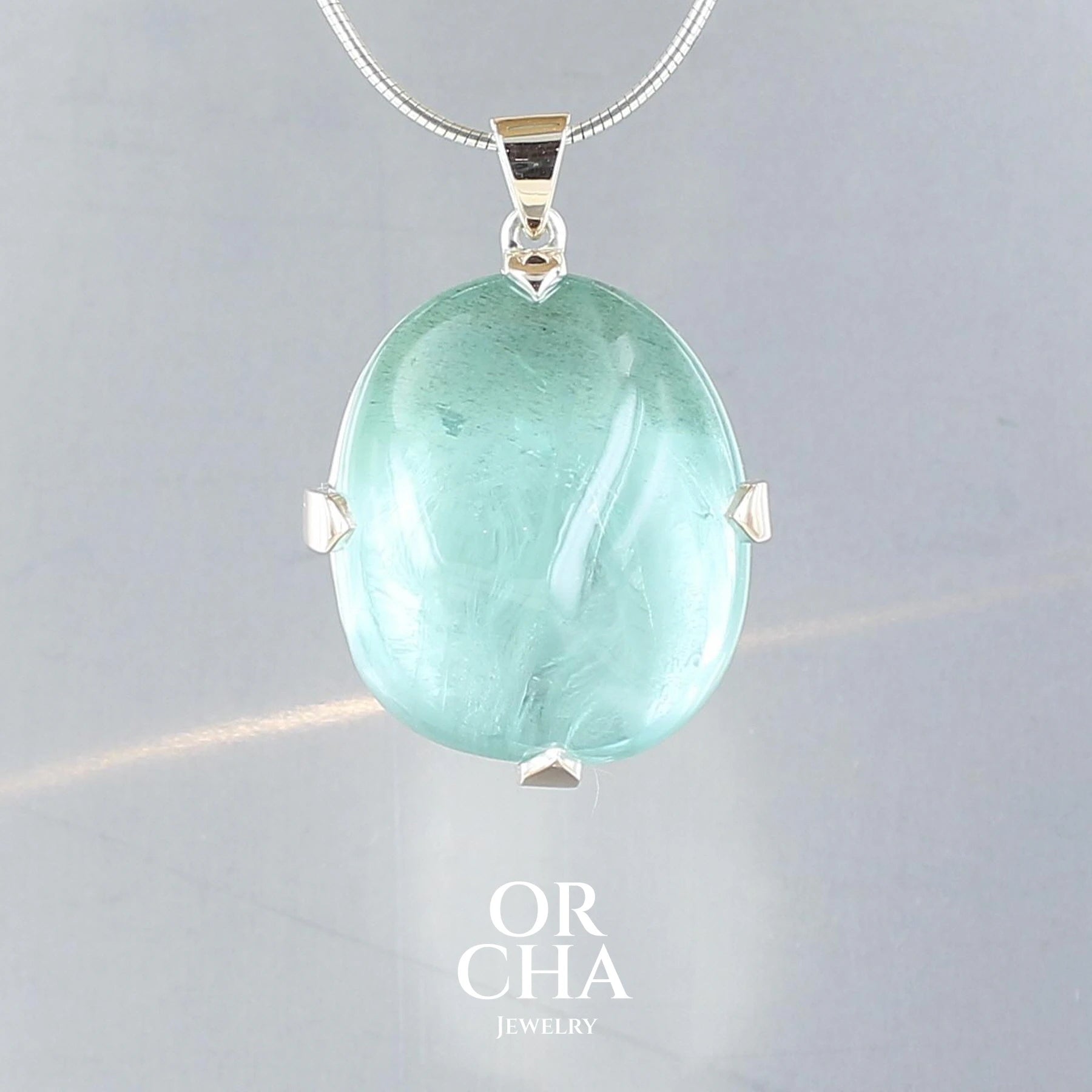 Pendentif en or 9k et argent massif 925 serti d’une Aigue-marine de 62 carats, pierre naturelle de couleur bleu verte. Ce bijou est une création originale fabriqué à la main de manière traditionnelle. Un cadeau unique, éthique et durable présenté dans un coffret de notre marque, prêt à offrir.