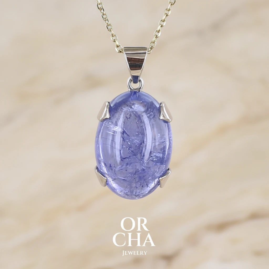 pendentif pour femme en or 9k et argent massif serti d'un cabochon de Tanzanite de 46,3 carats, de couleur bleu lavande foncé profond et intense. Pierre transparente présentant des inclusions. Pierre ayant subit un traitement de chauffe, traitement admis et fréquent en gemmologie pour ce type de pierre . Bijoux unique, éthique et durable présenté dans un coffret de notre marque, prêt à offrir. Livraison offerte, certificat d'authenticité, service client.